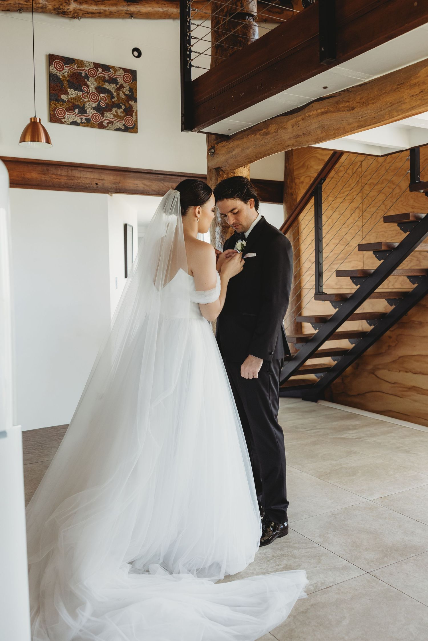 Wedding couple shares intimate moments in a rustic indoor venue with wooden beams.
