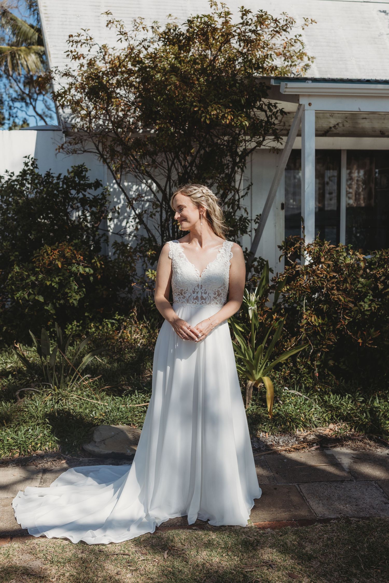 Elegant white wedding gown photographed against autumn garden backdrop.