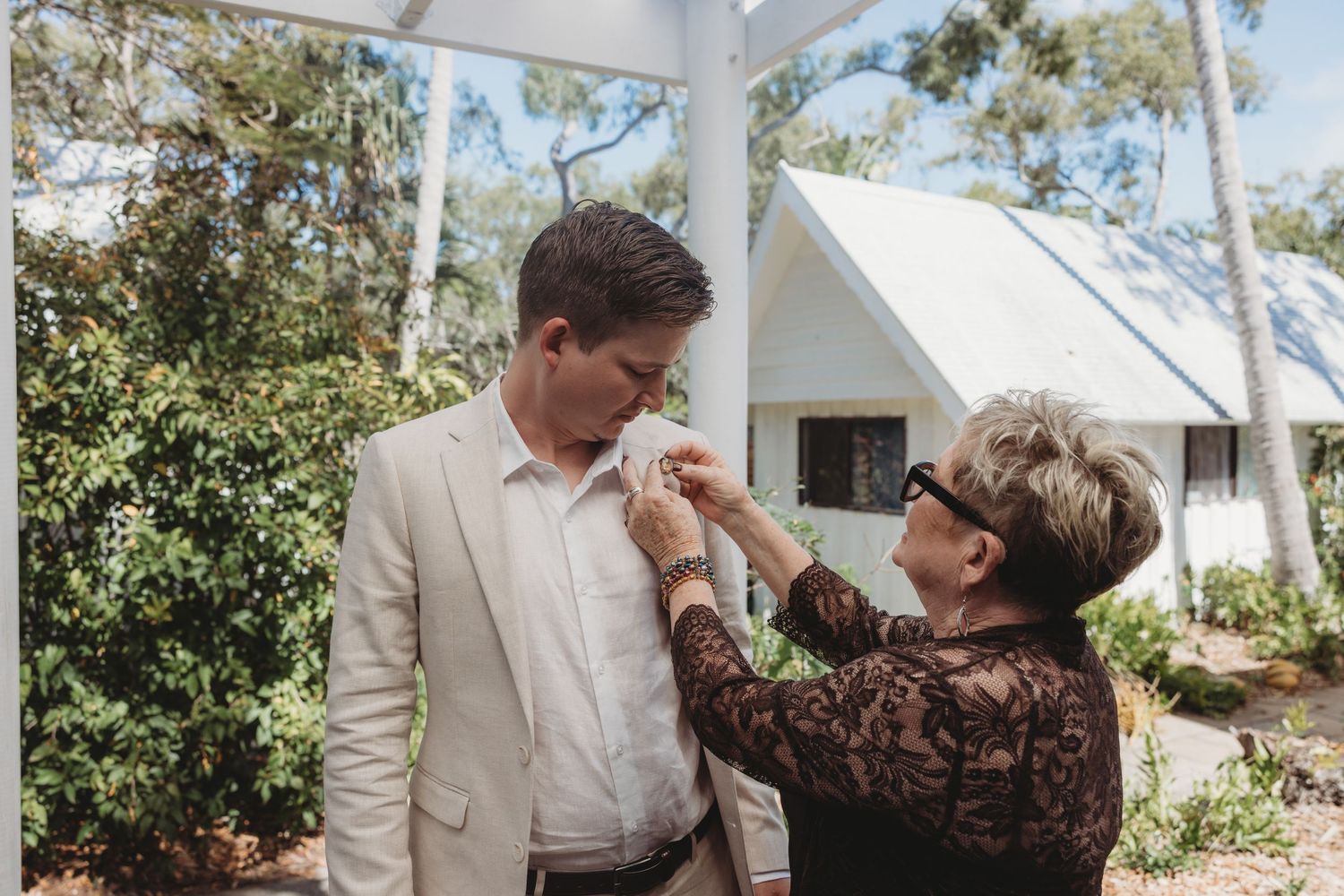 Wedding preparation moment captured in a sunlit outdoor garden setting.