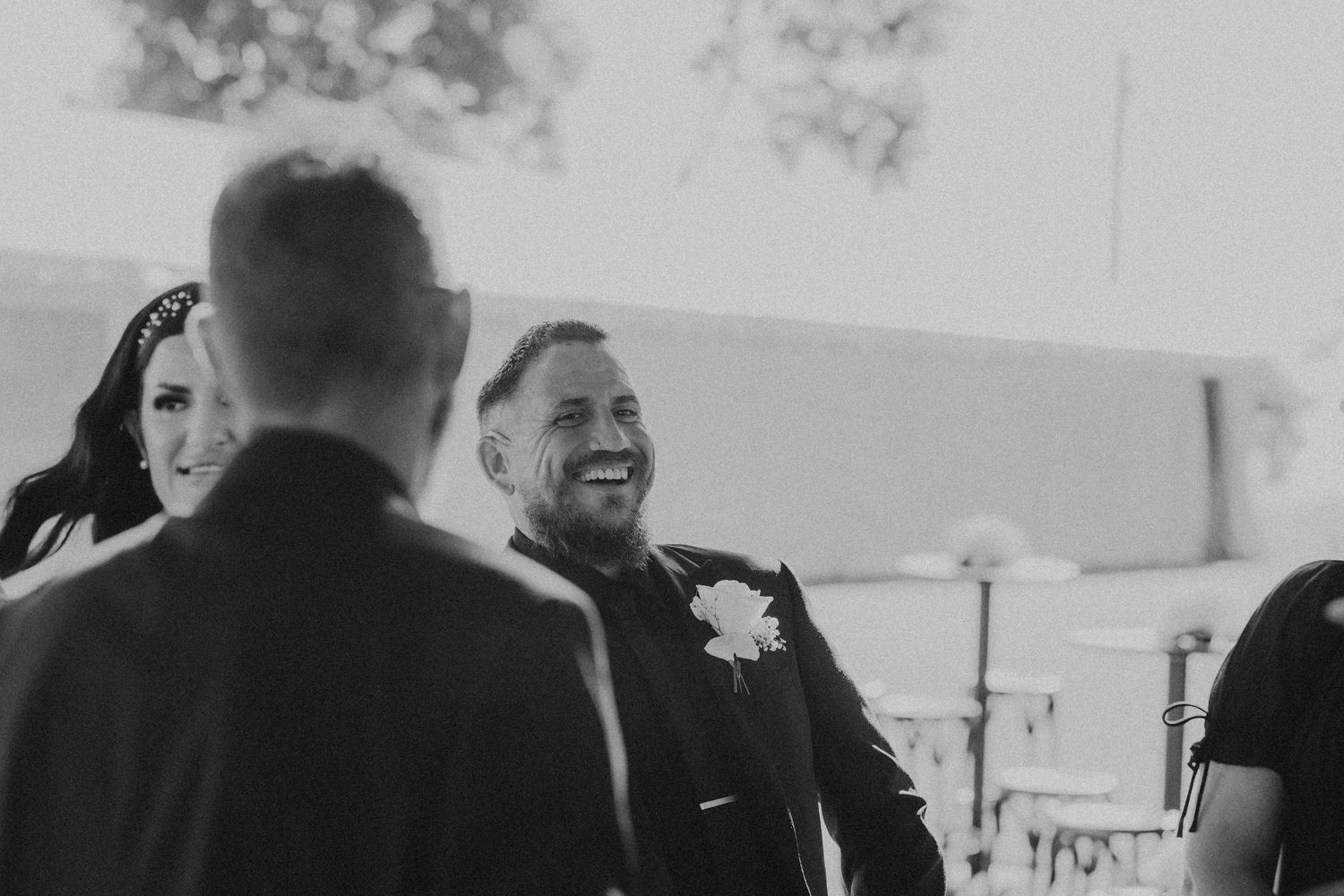 Black and white candid moment from an outdoor wedding ceremony.