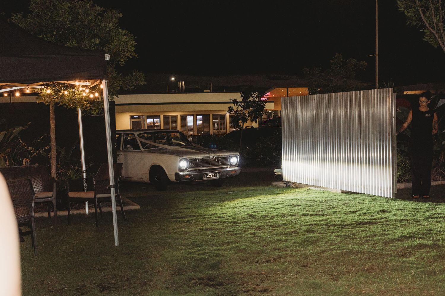 Nighttime outdoor venue setting with string lights and illuminated structures.