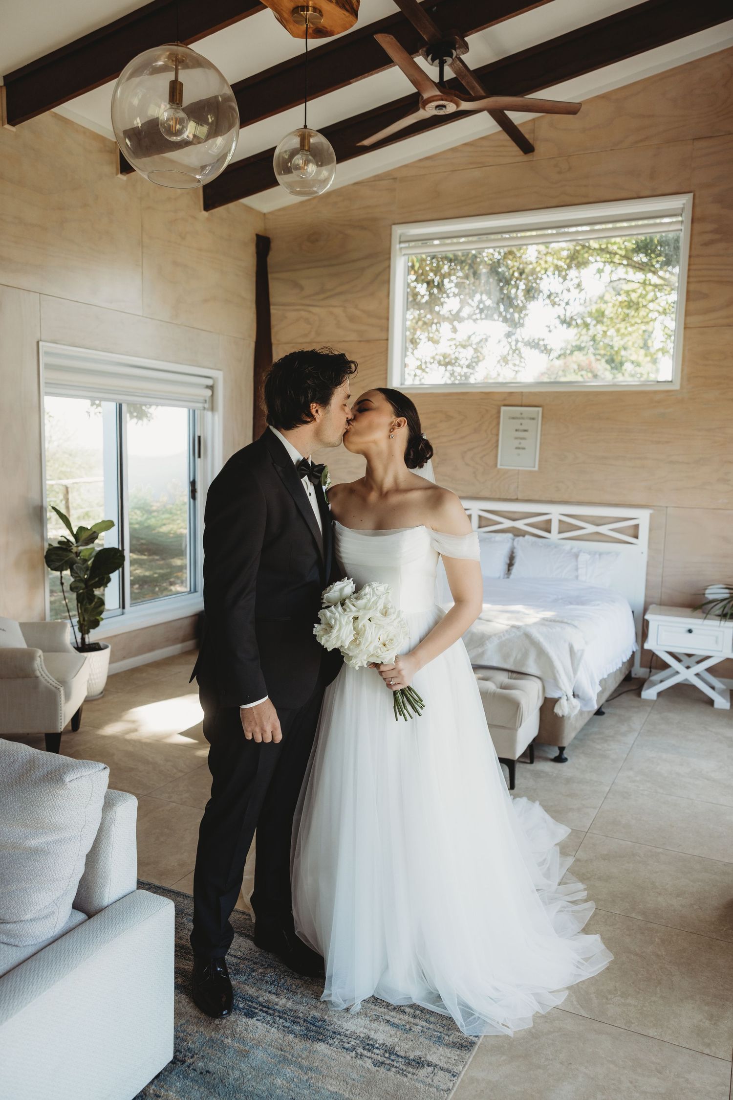 A romantic first look moment between newlyweds in a light-filled room with wooden walls.