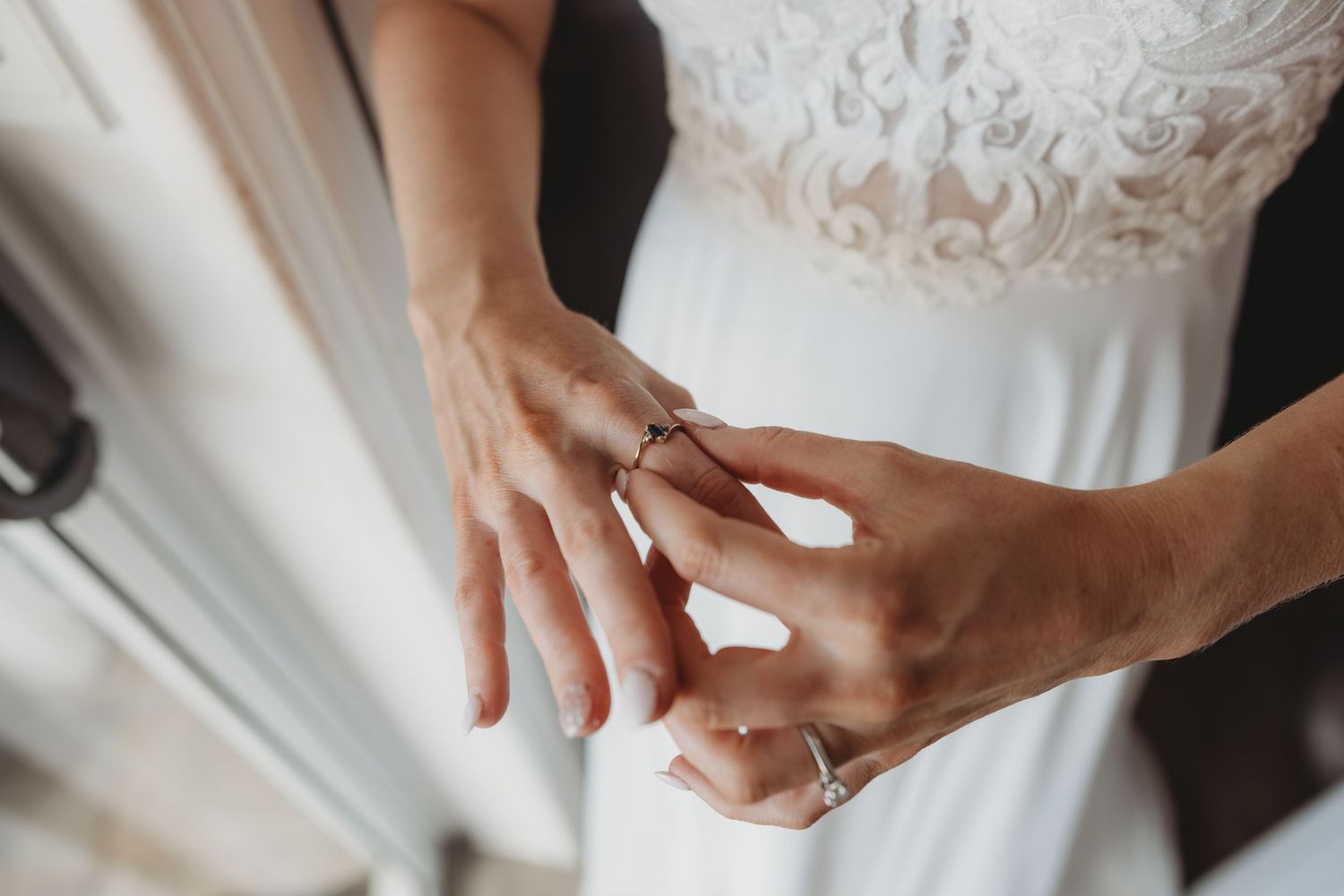 Detail shots of hands adjusting a white lace wedding dress.