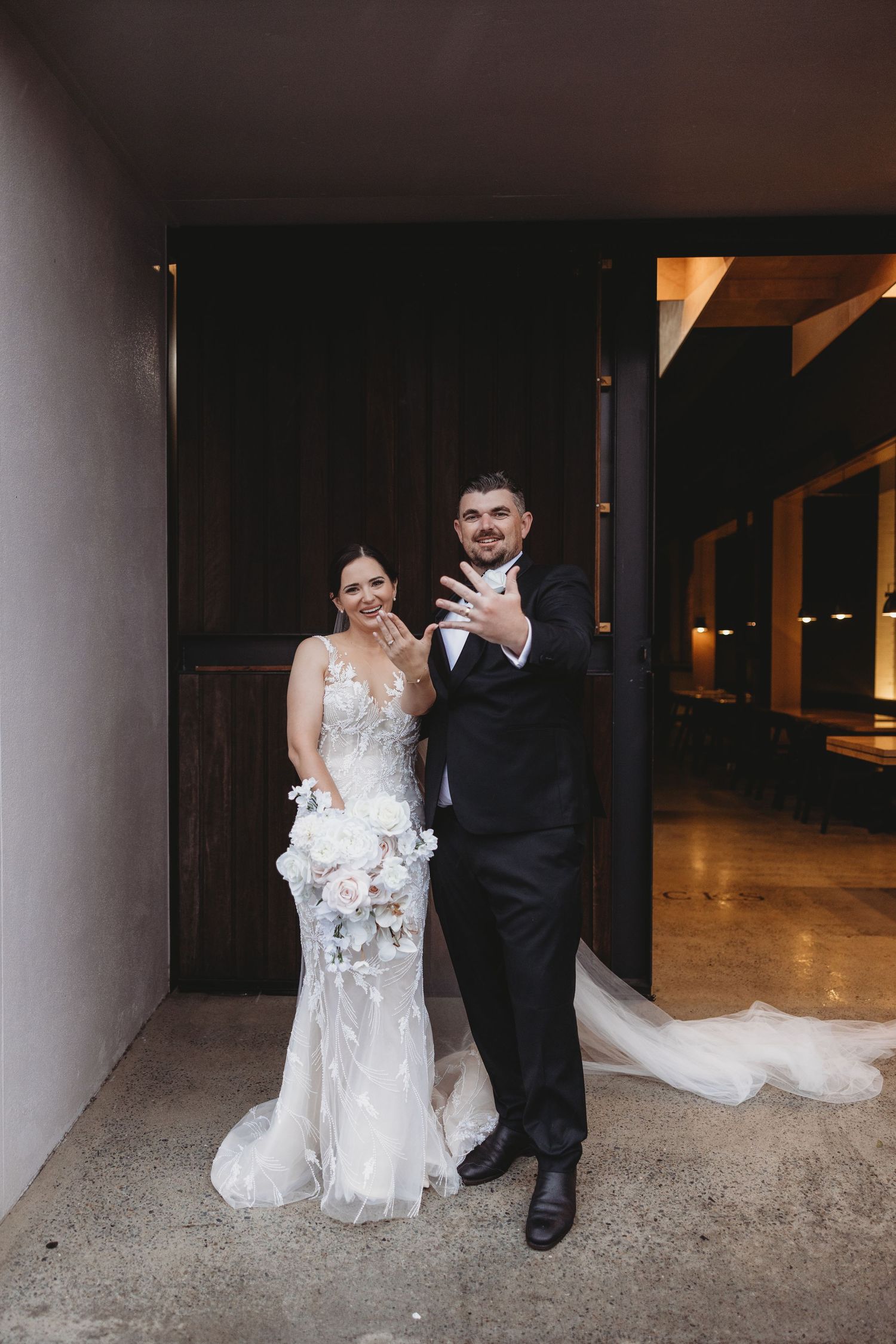 Couple shares intimate dance moments in an indoor venue with concrete pillars and dramatic lighting.