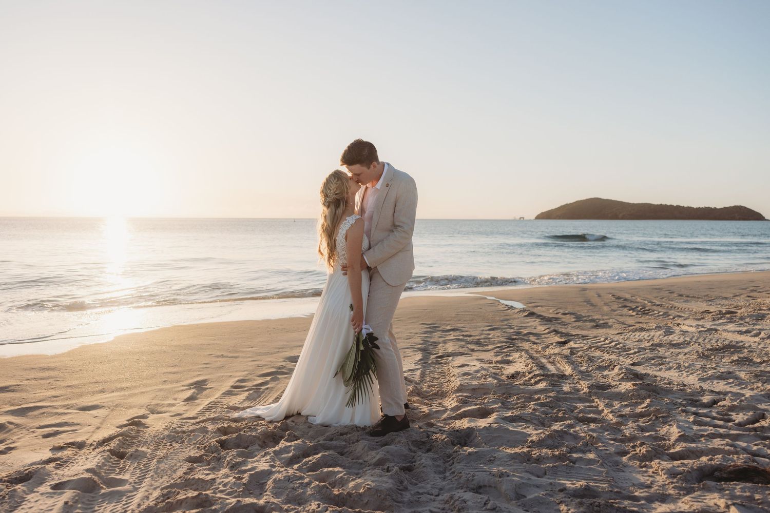 Sunset beach wedding photography session with waves and coastline in background.