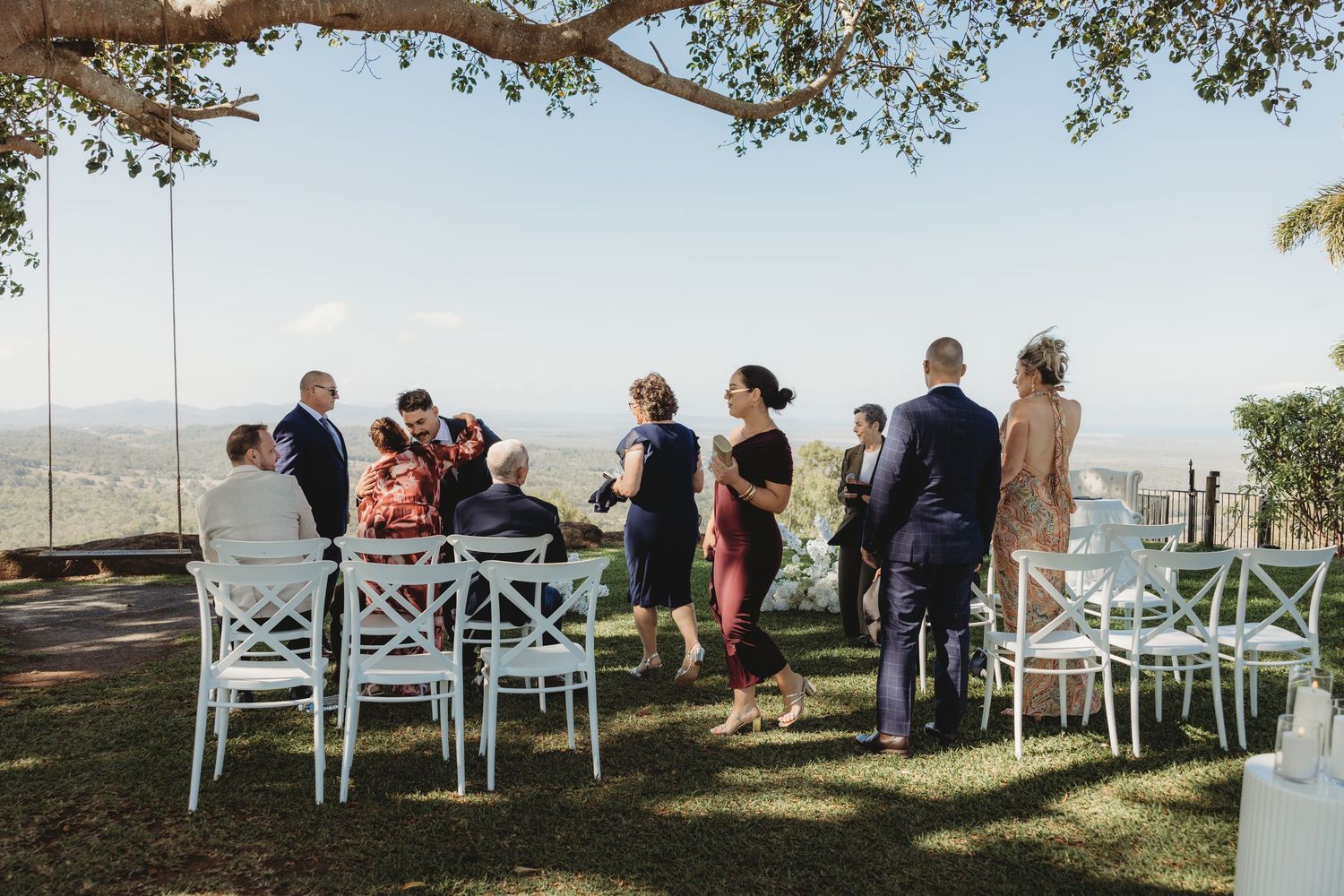 White cross-back chairs arranged in rows on a hilltop for an outdoor wedding ceremony.