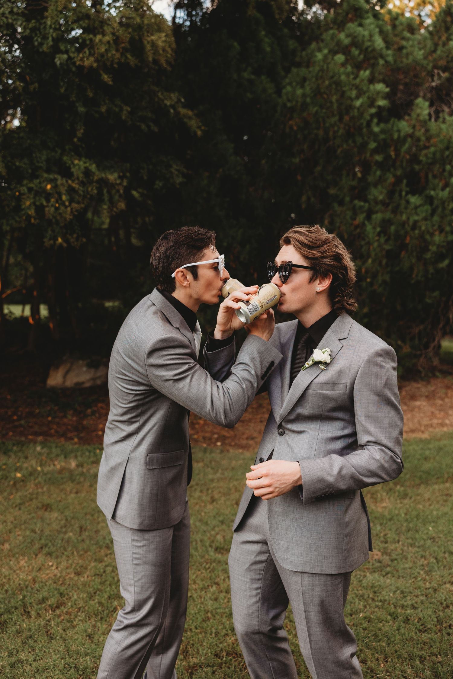 Two people in matching grey suits share playful moments during wedding photos Rockhampton Botanical Gardens