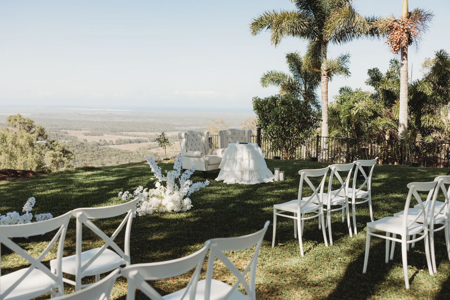 White chairs set up for an outdoor wedding ceremony with scenic mountain views in the background.