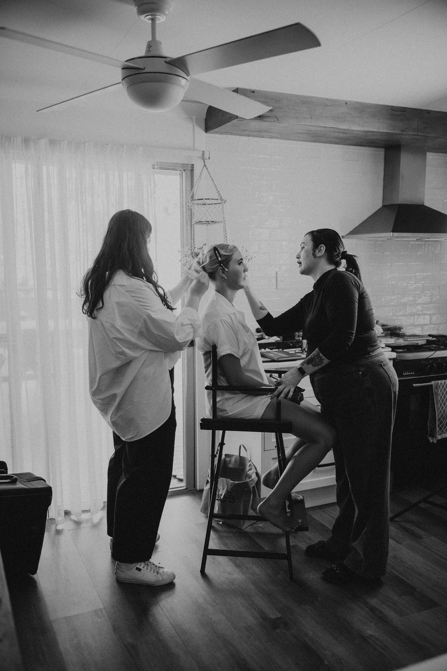 Black and white photo of wedding preparations in a room with hardwood floors.