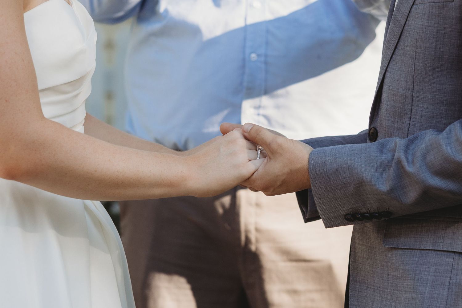 Close-up of hands exchanging rings during an outdoor wedding ceremony St Aubins