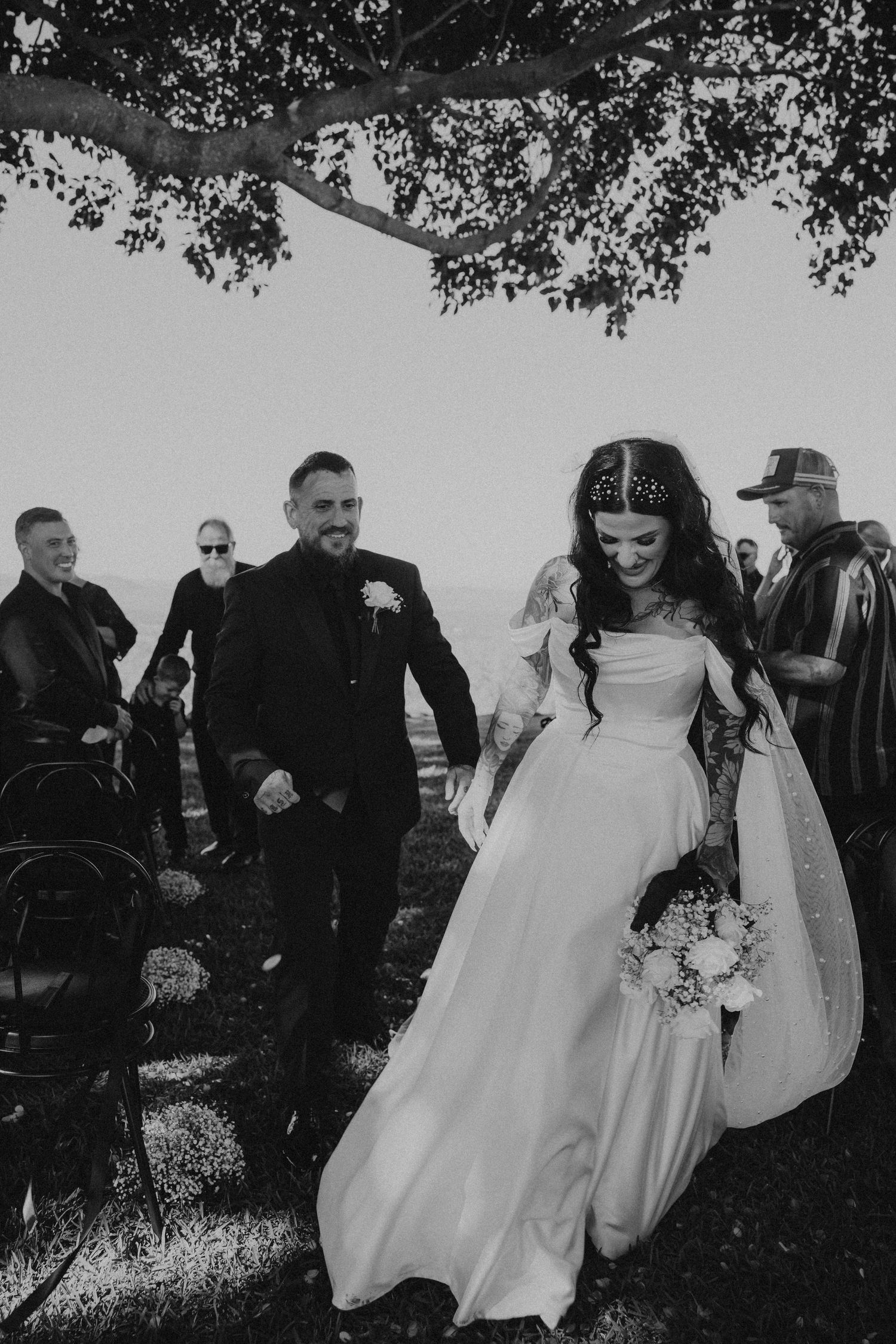 A black and white wedding photo sequence showing joyful moments under trees outdoors.