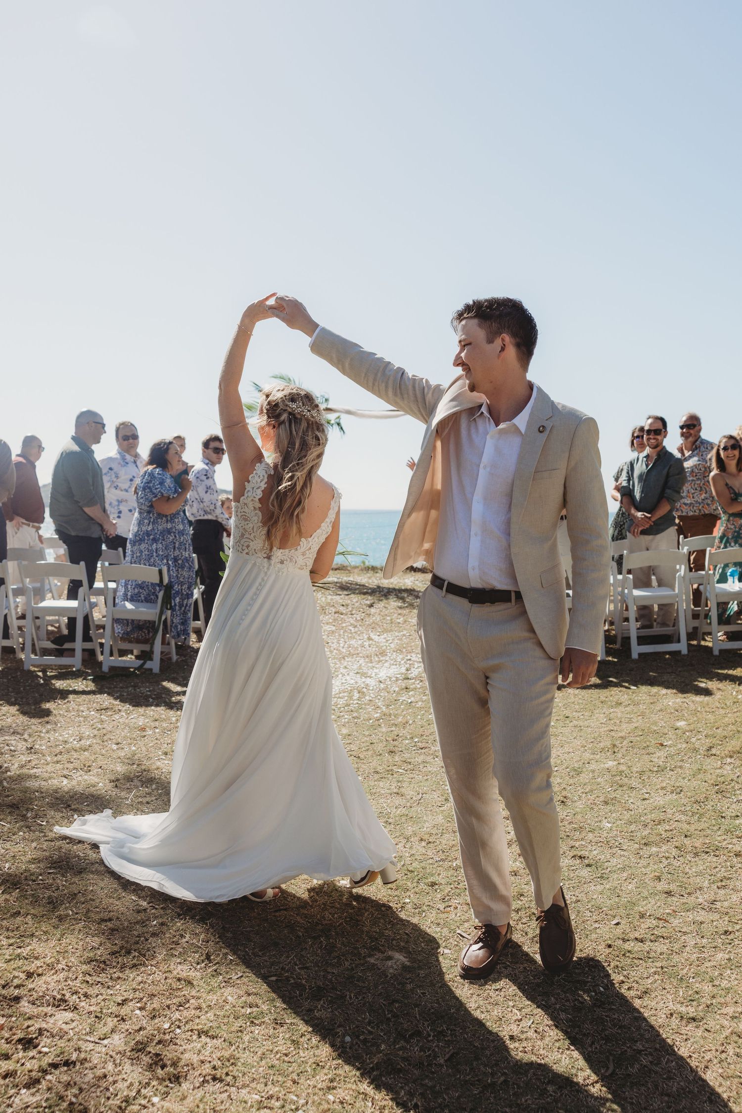 Newlyweds celebrate with joyful dance moves at beachside ceremony.
