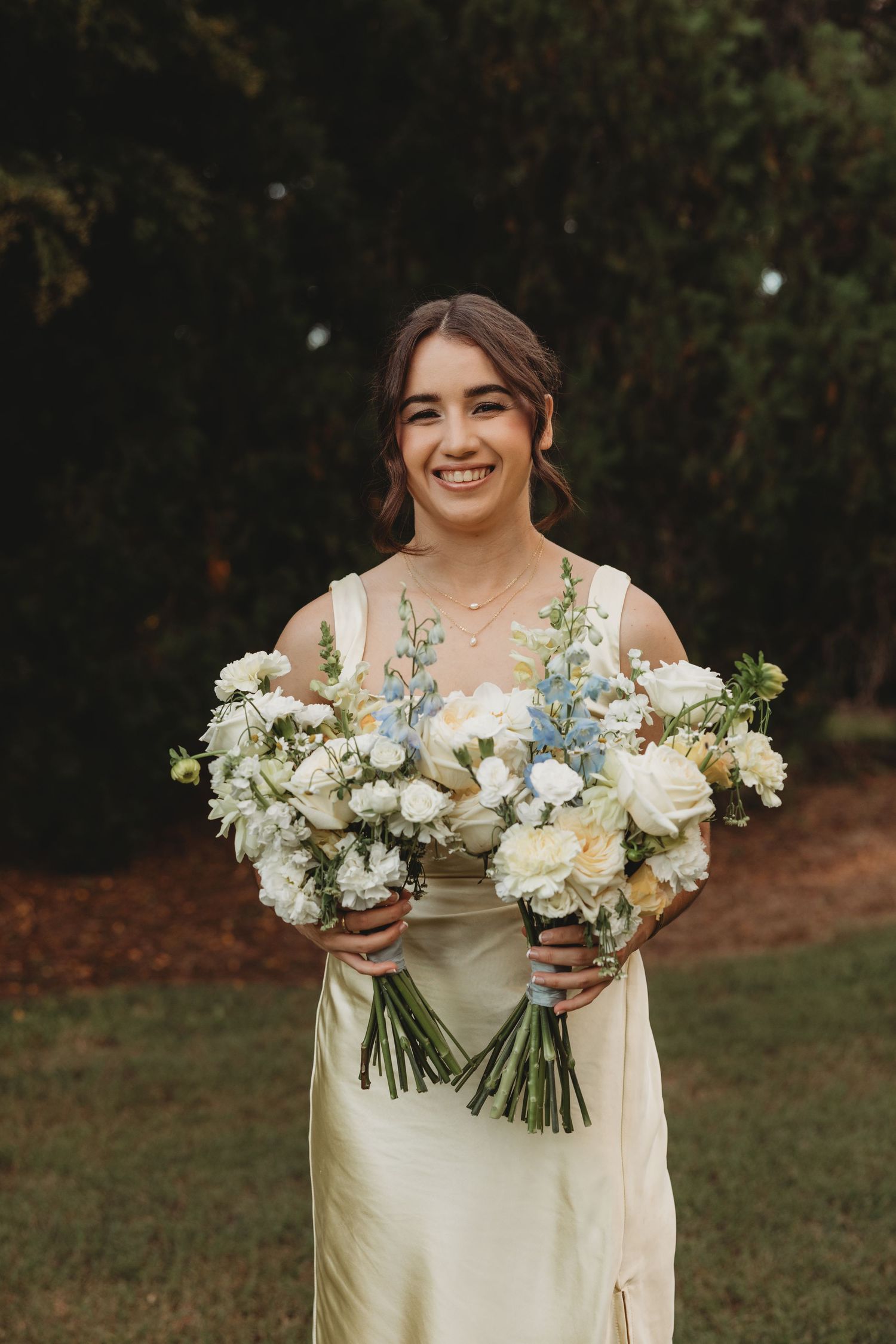 A bridesmaid in cream dress holds beautiful white and blue floral bouquets Lilly & Lotus Florals rockhampton wedding