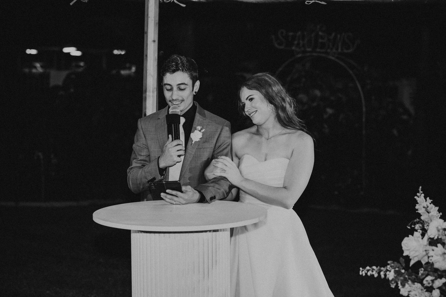 Black and white photo of a couple at their wedding reception with elegant table settings.