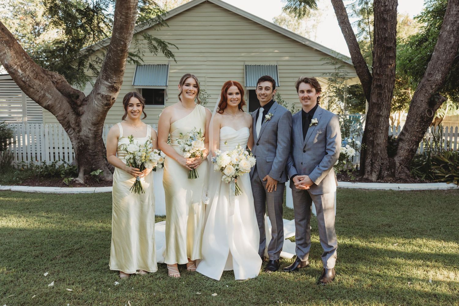 Wedding party poses in front of a beige house with bridesmaids in cream dresses St Aubins Weddings