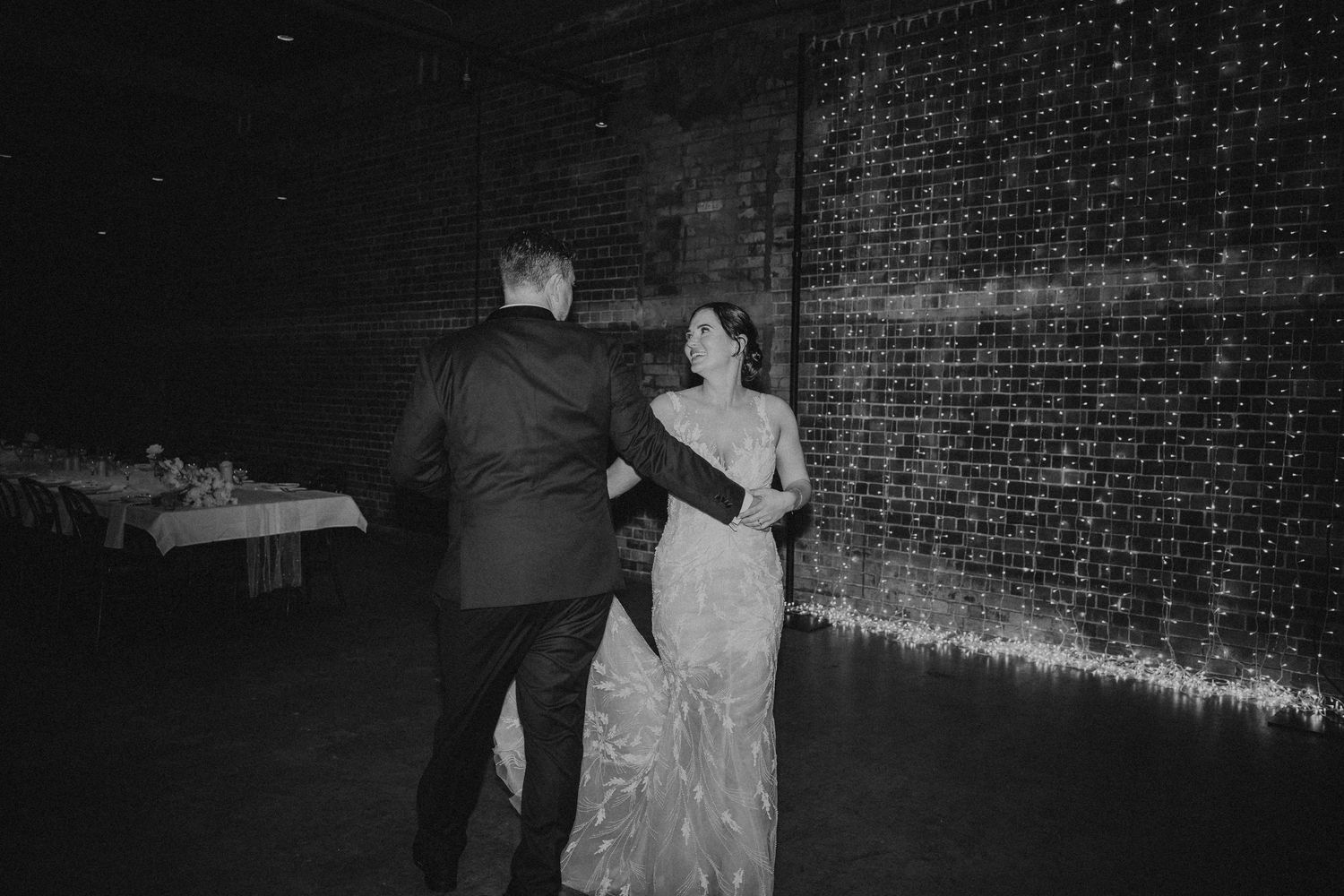 Wedding reception venue with fairy light backdrop and dance floor.
