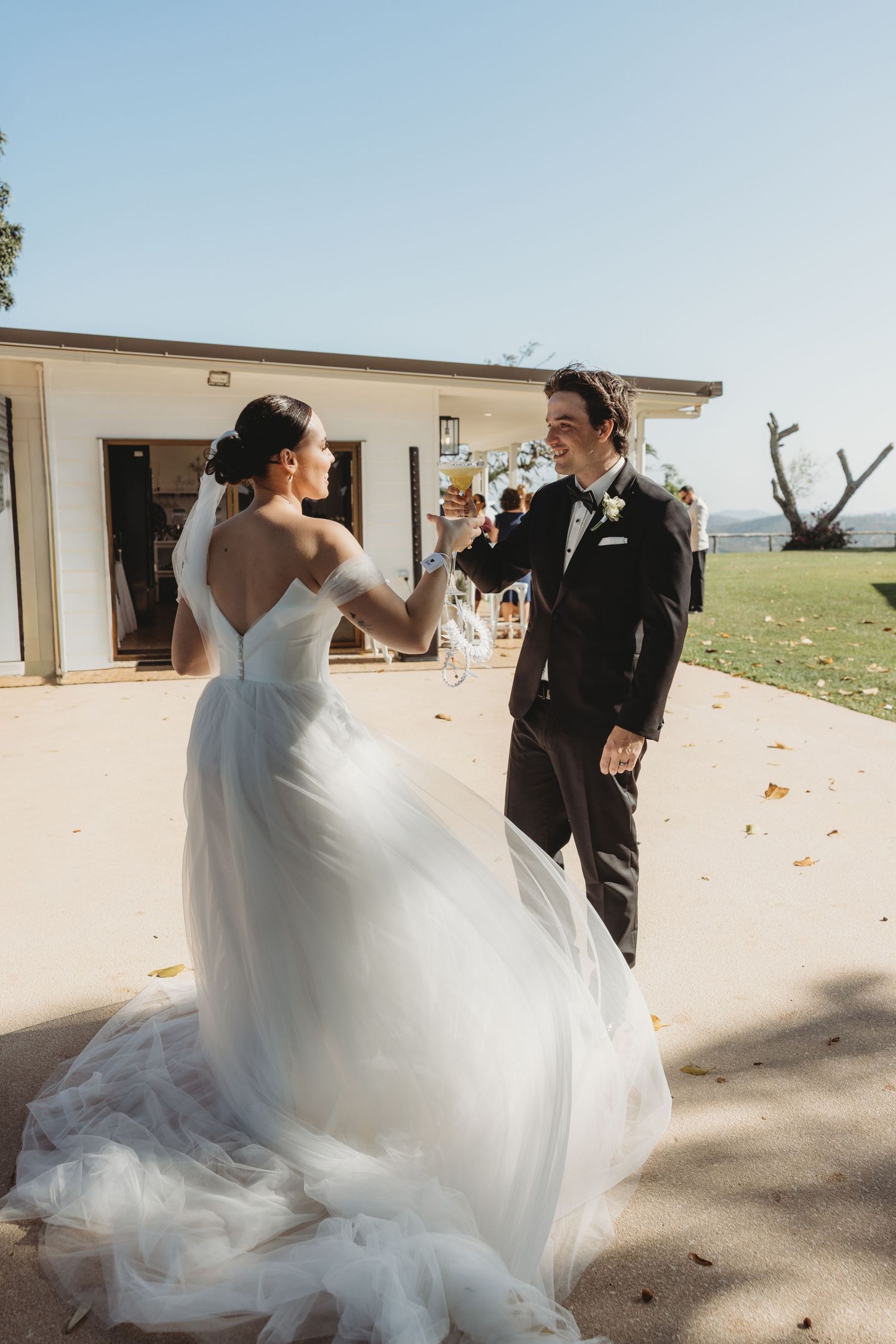 Bride in flowing white dress twirls on a sunny patio during wedding celebrations.