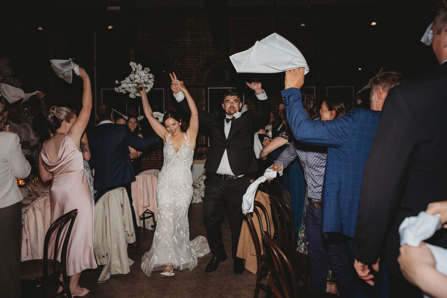 Wedding celebration with guests dancing and celebrating on a dark dance floor.