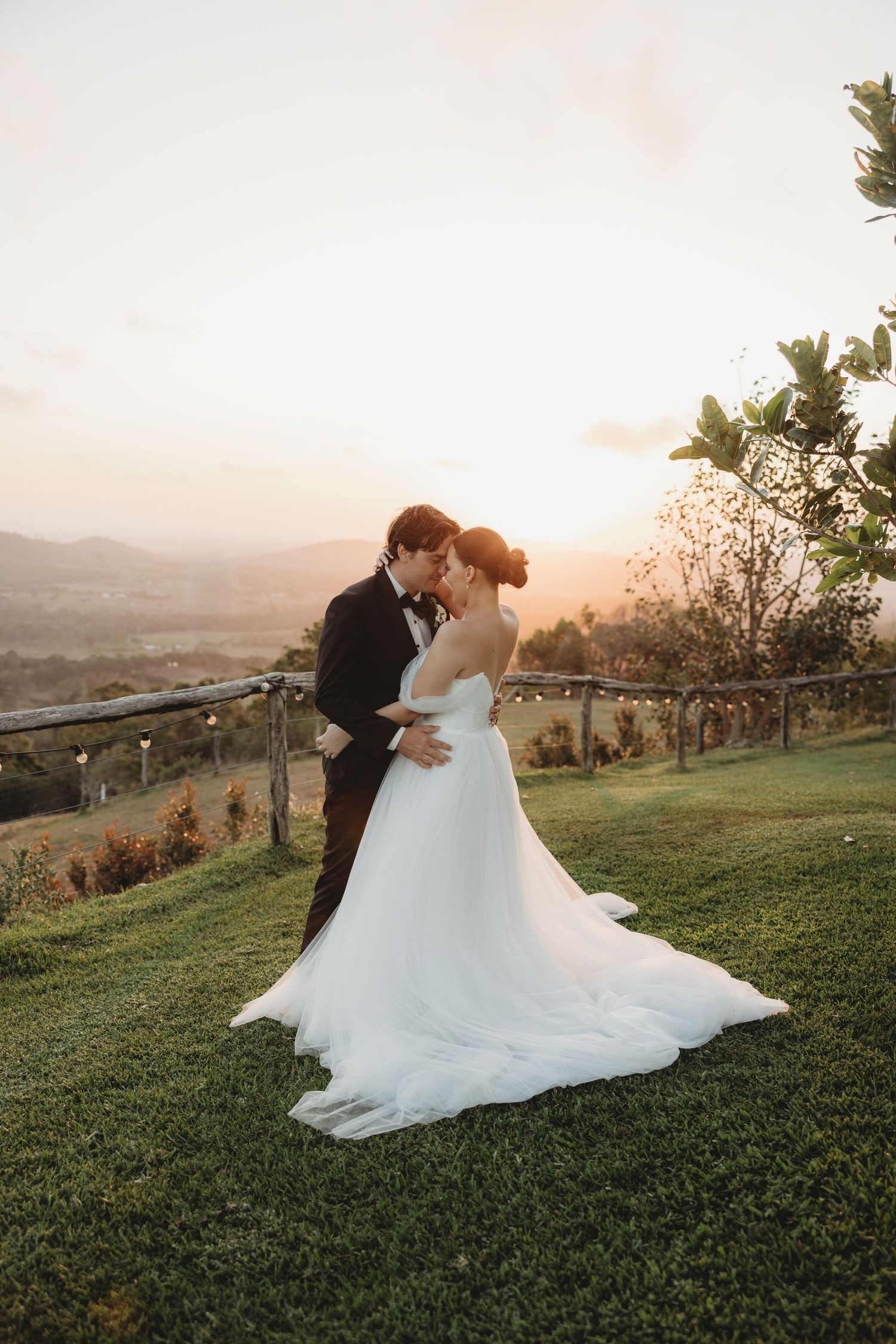 Bride's dress flows beautifully during sunset portrait session on hilltop.