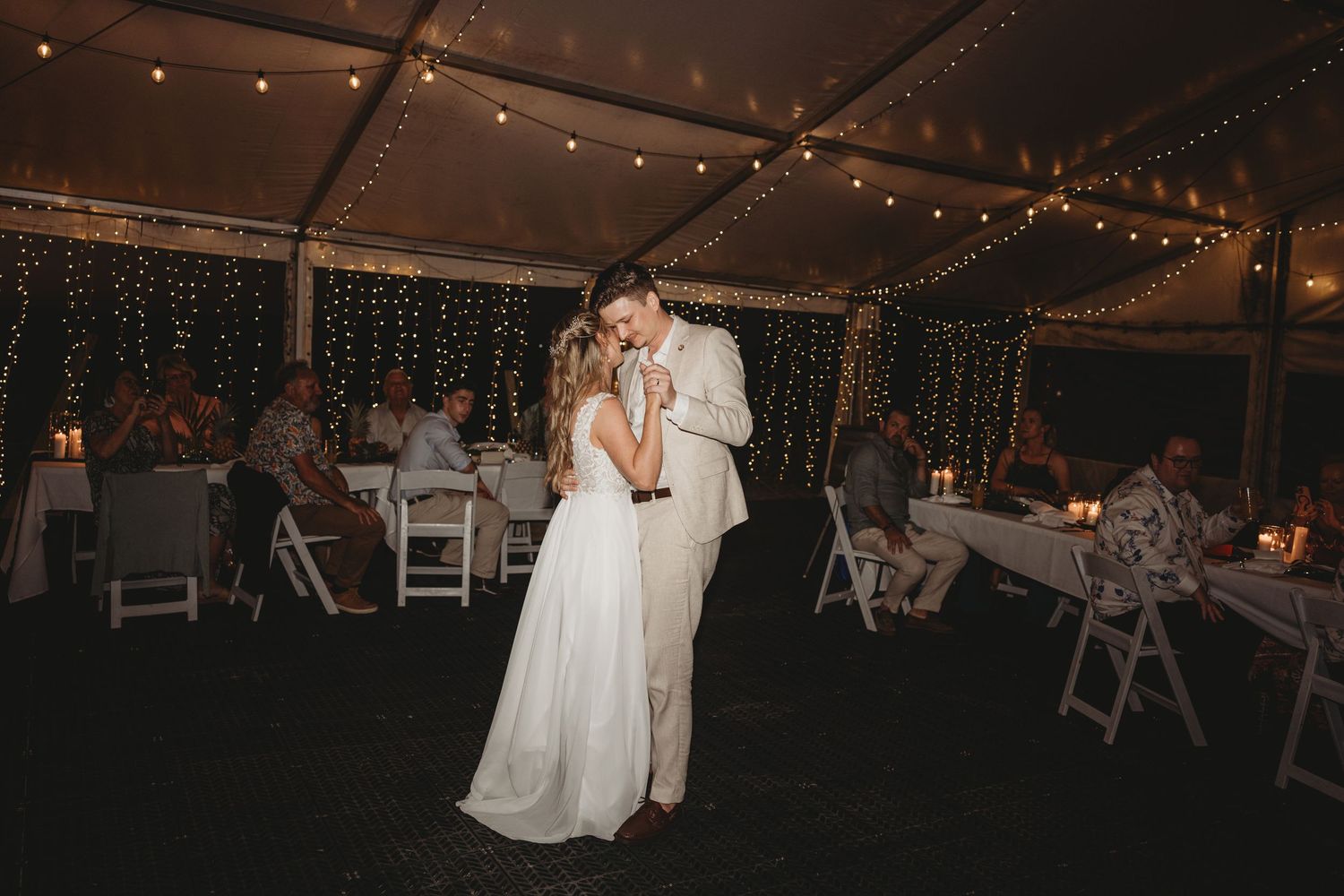 String lights illuminate a wedding reception tent creating a warm ambiance.