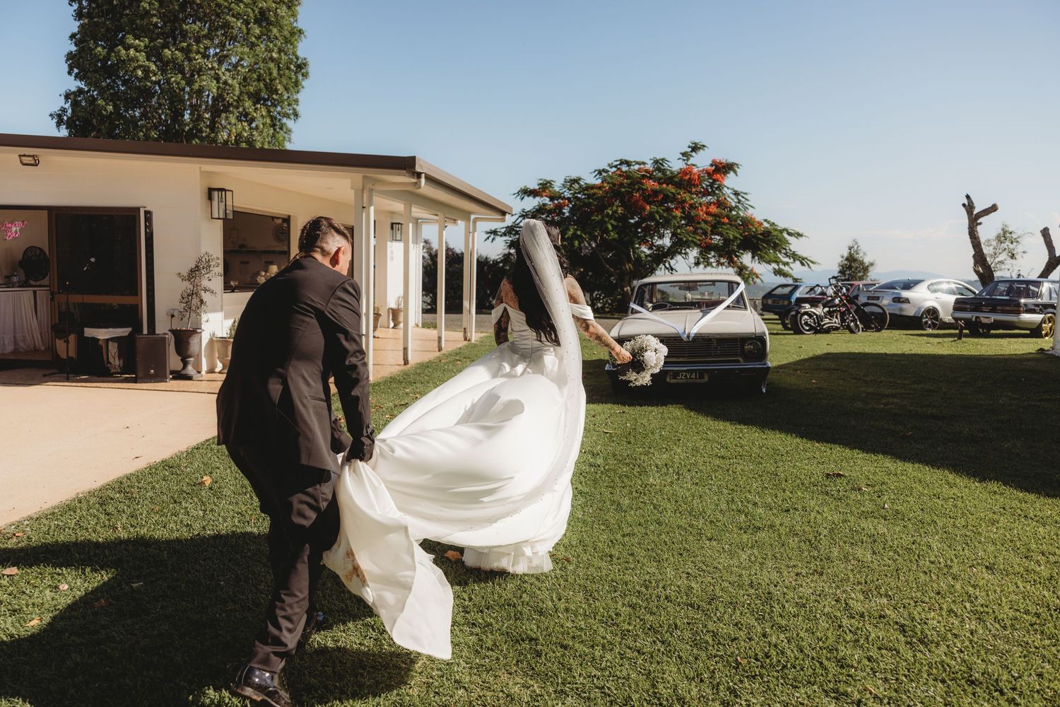 A wedding celebration takes place on a sunny lawn with guests and decorations.