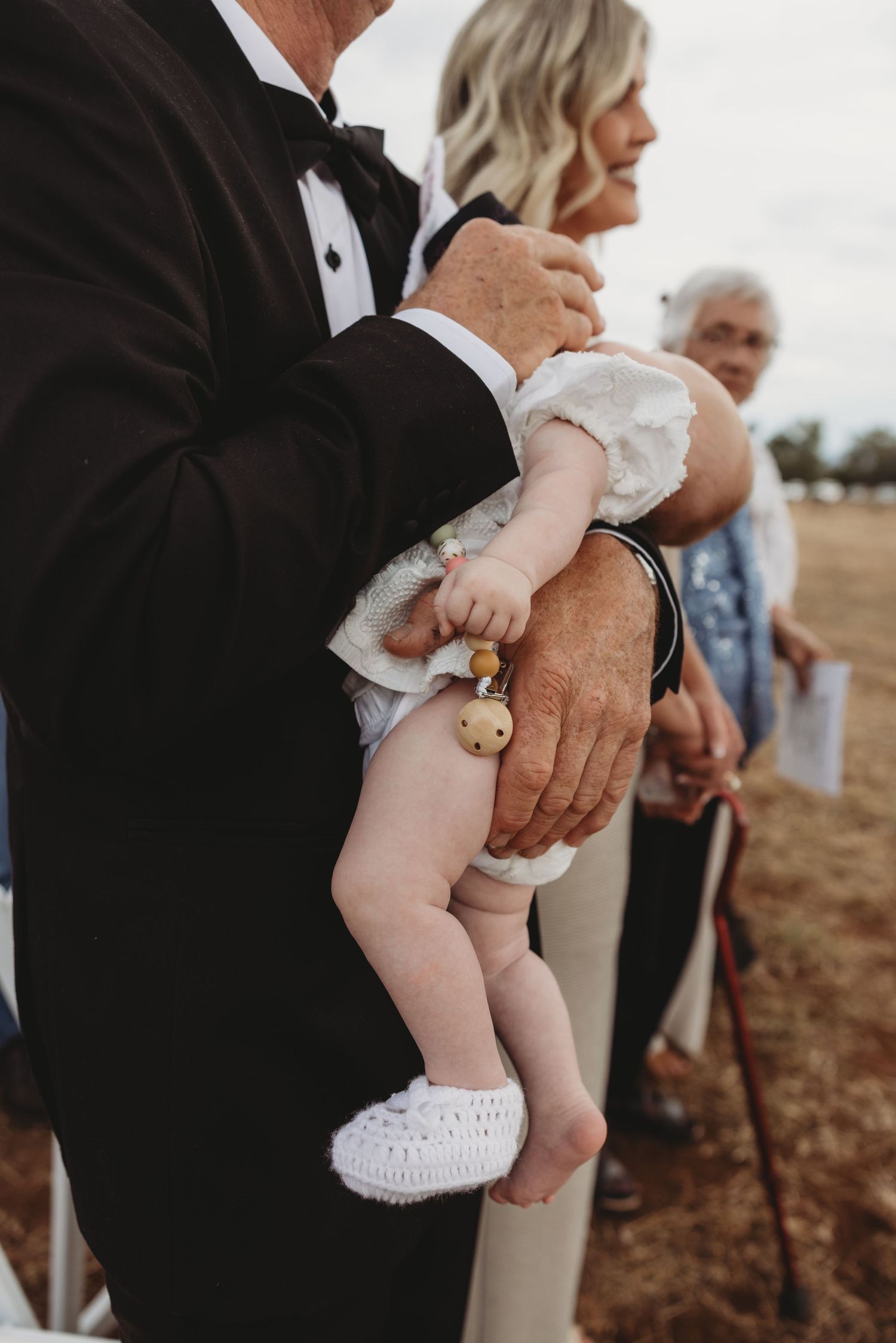 Close-up shots of a baby being held during a formal wedding event.