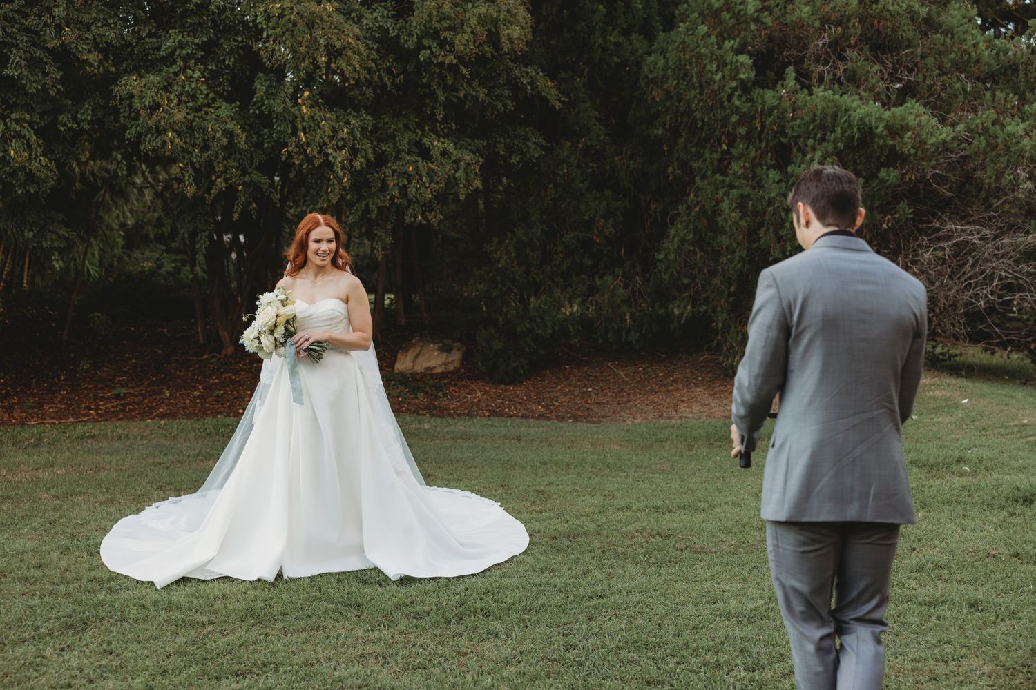 Couple takes wedding photos on a grassy lawn with trees in the background Rockhampton Botanical Gardens