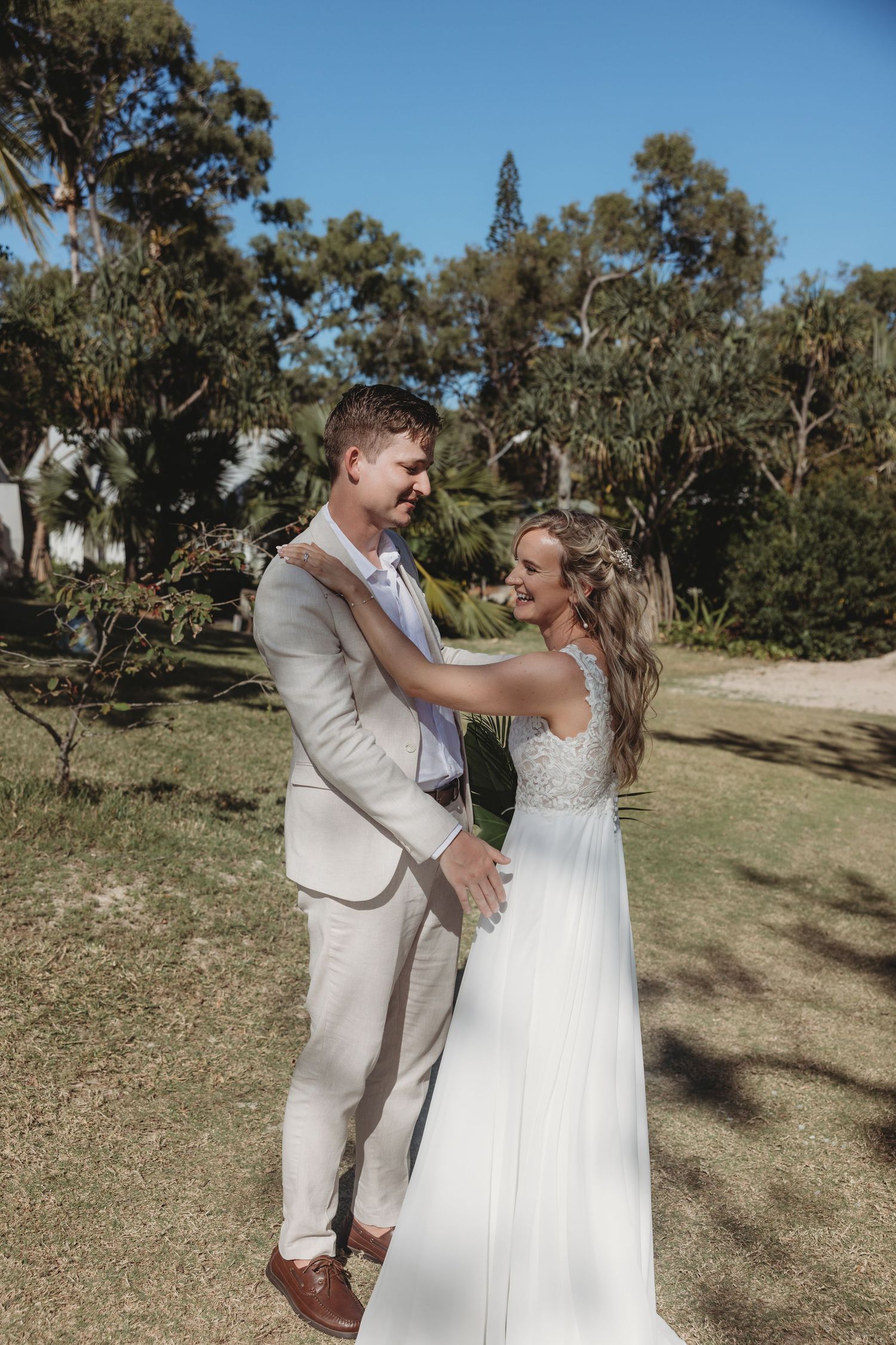 A couple shares a joyful dance moment outdoors surrounded by trees and natural lighting.