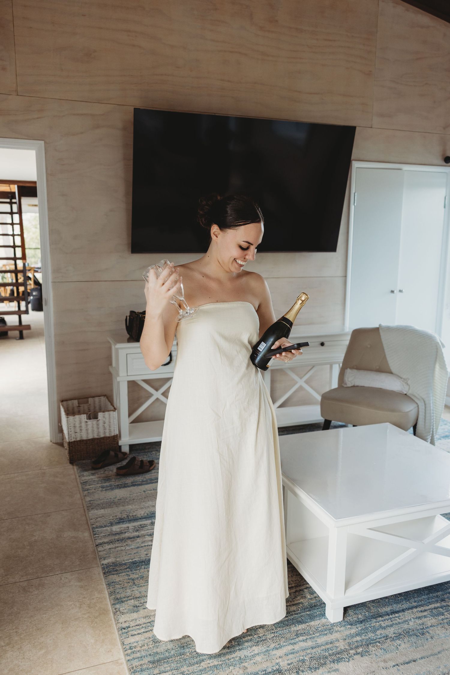 A white dress flows gracefully in an elegant room with wooden walls and modern furniture.