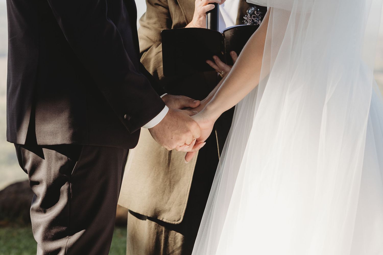 Close-up view of flowing white wedding dress fabric during an outdoor ceremony.