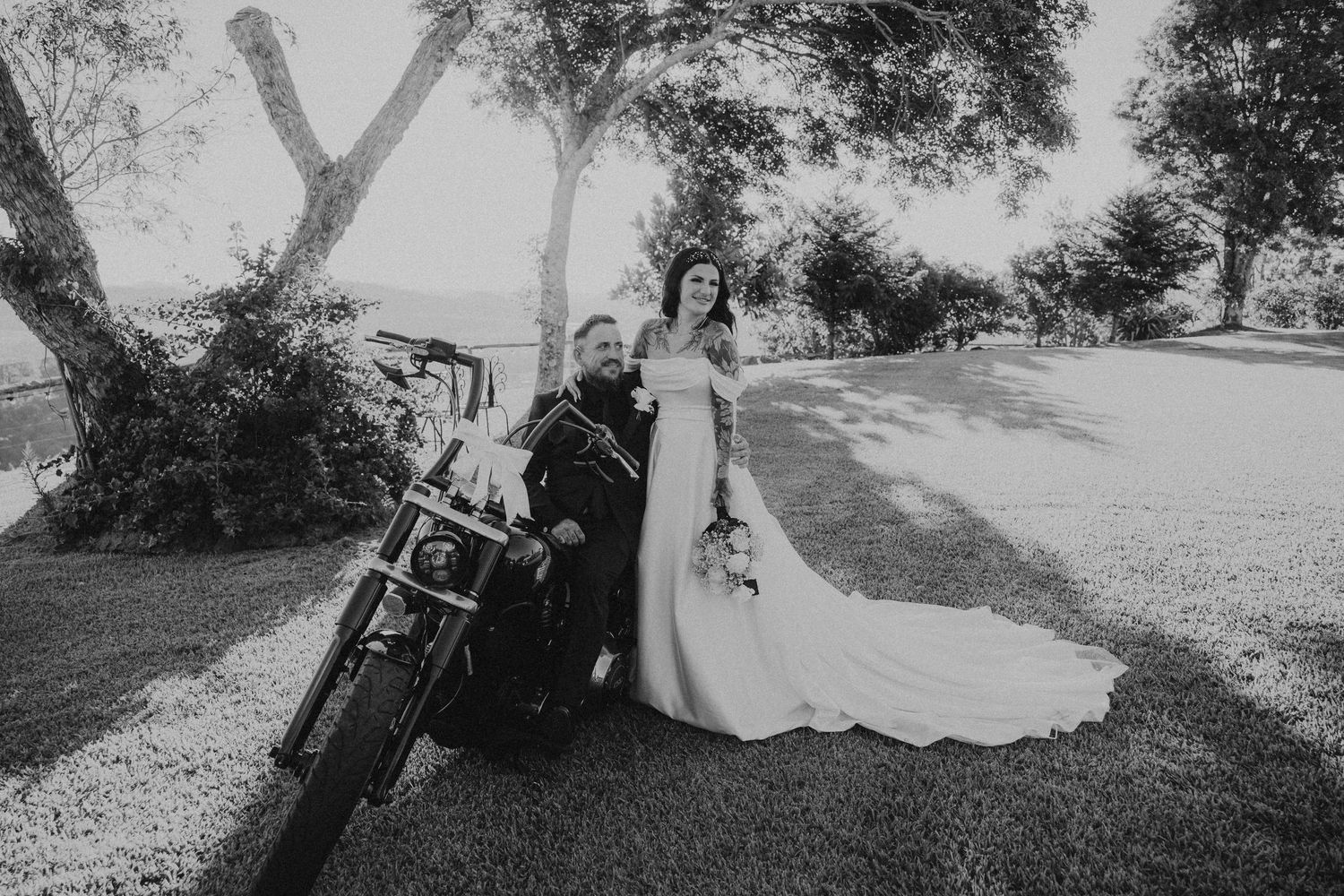 Black and white outdoor wedding photography scene with trees and natural lighting.