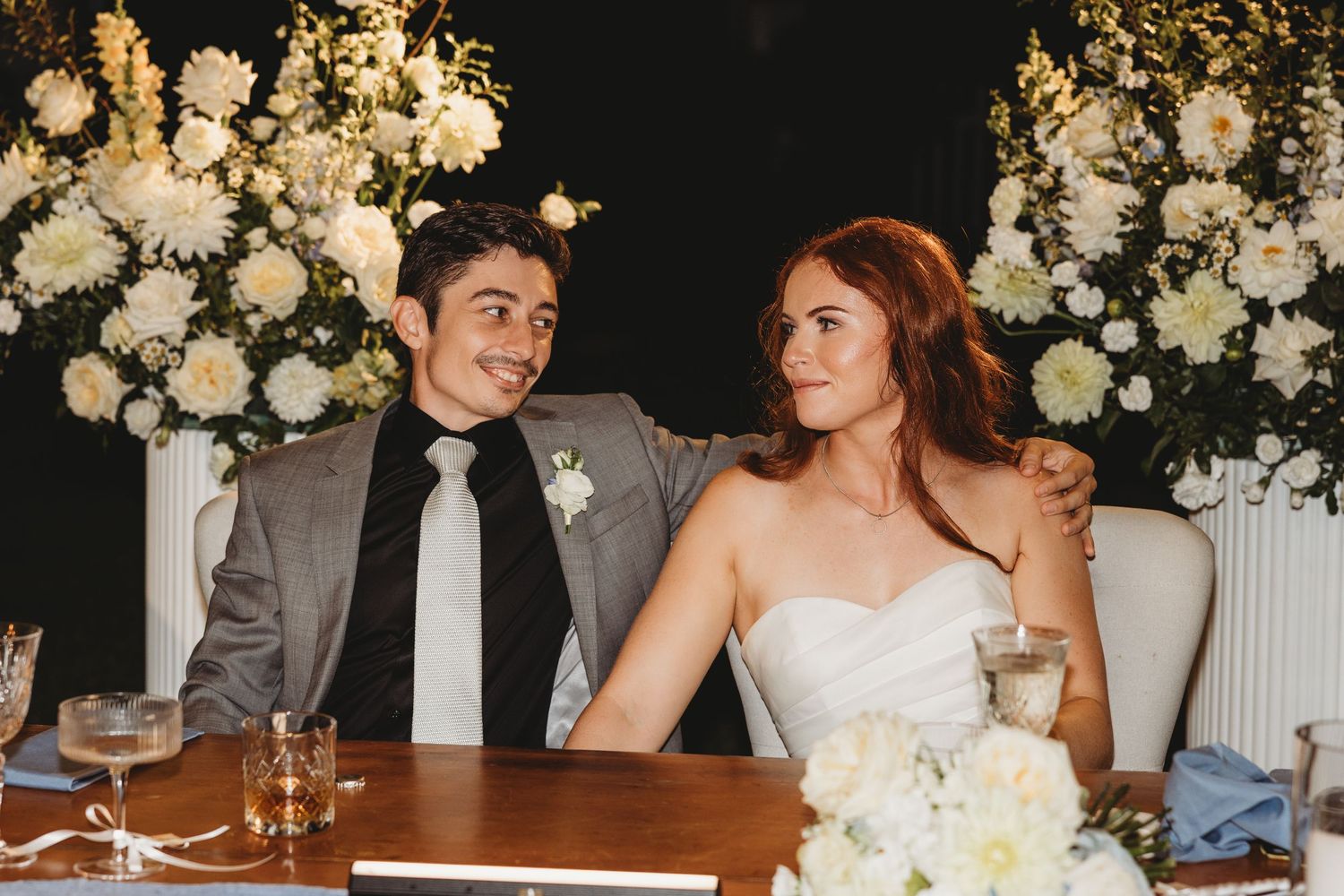 Wedding reception table adorned with white floral arrangements and ambient lighting.