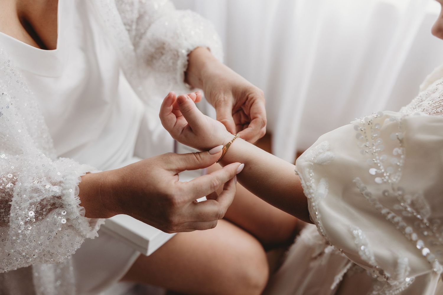 A close-up view of hands adjusting delicate white lace details on a wedding dress.