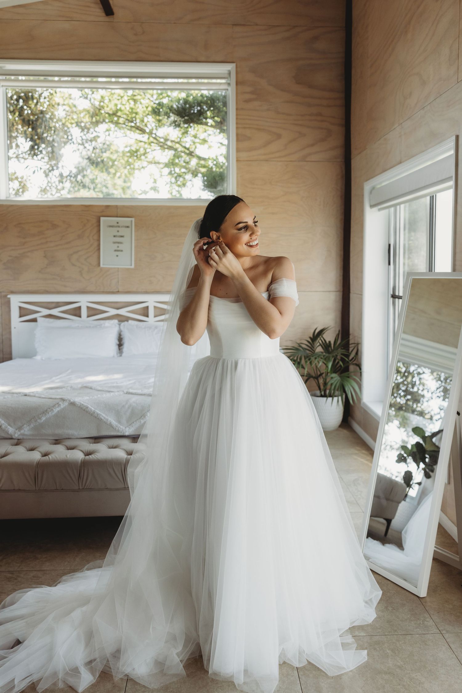Bride twirling in a voluminous tulle wedding dress in front of large windows.