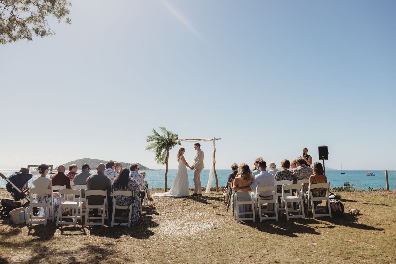 Wide angle view of beach wedding ceremony setup with chairs facing the ocean.