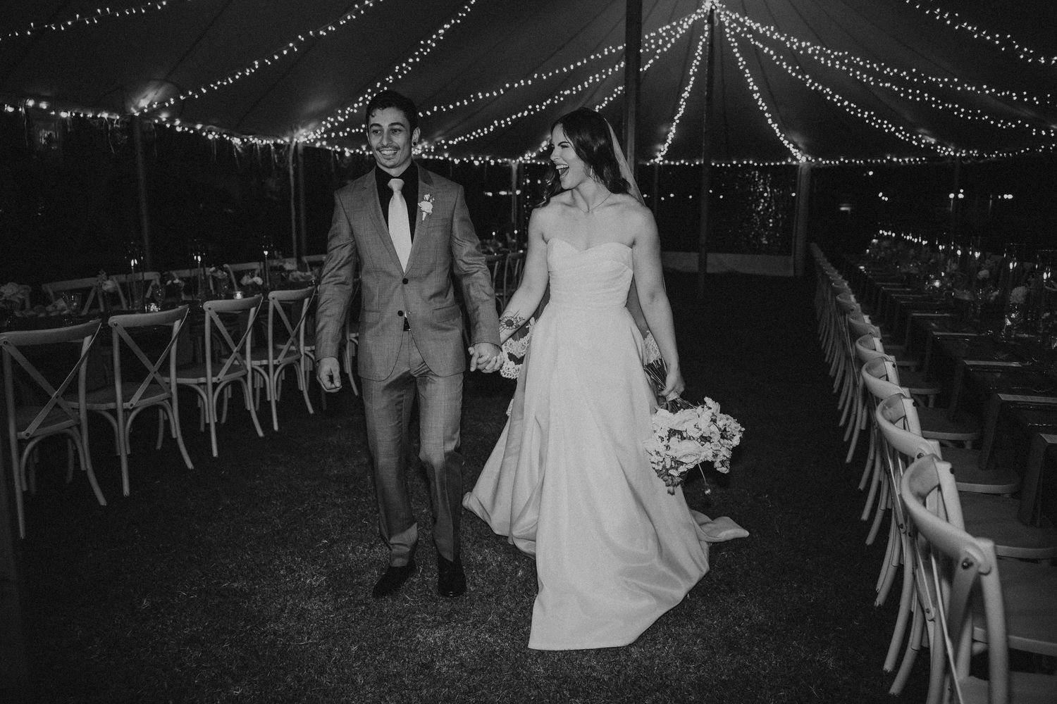 Evening wedding reception under a tent with string lights creating dramatic lighting. bride and groom St Aubins. lilly & lotus styling