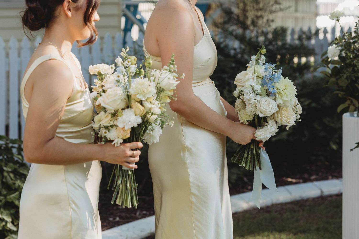 Bridesmaids in yellow dresses holding white floral bouquets during outdoor ceremony St Aubins