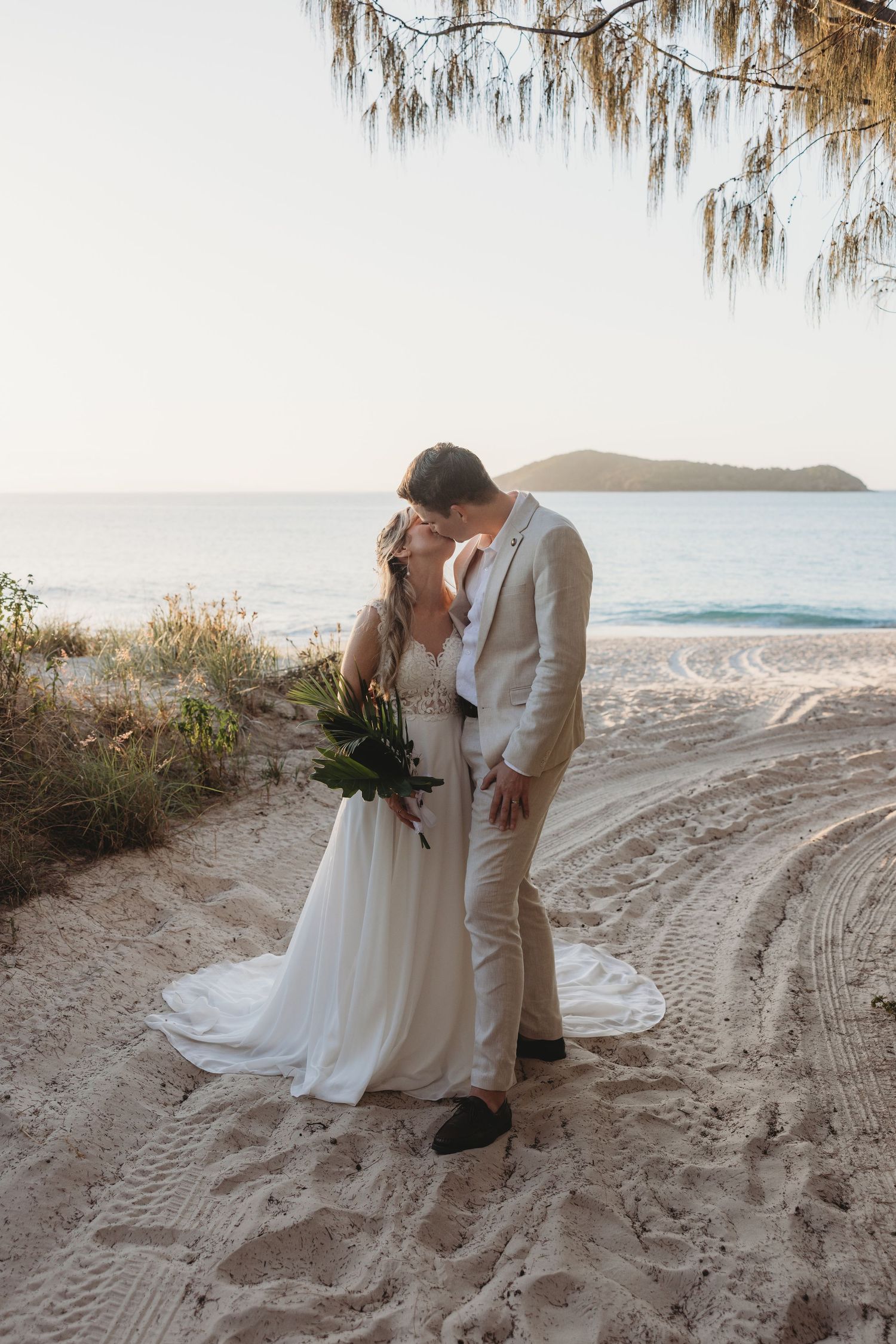 Romantic beachside wedding portraits with ocean and sand dunes in background.