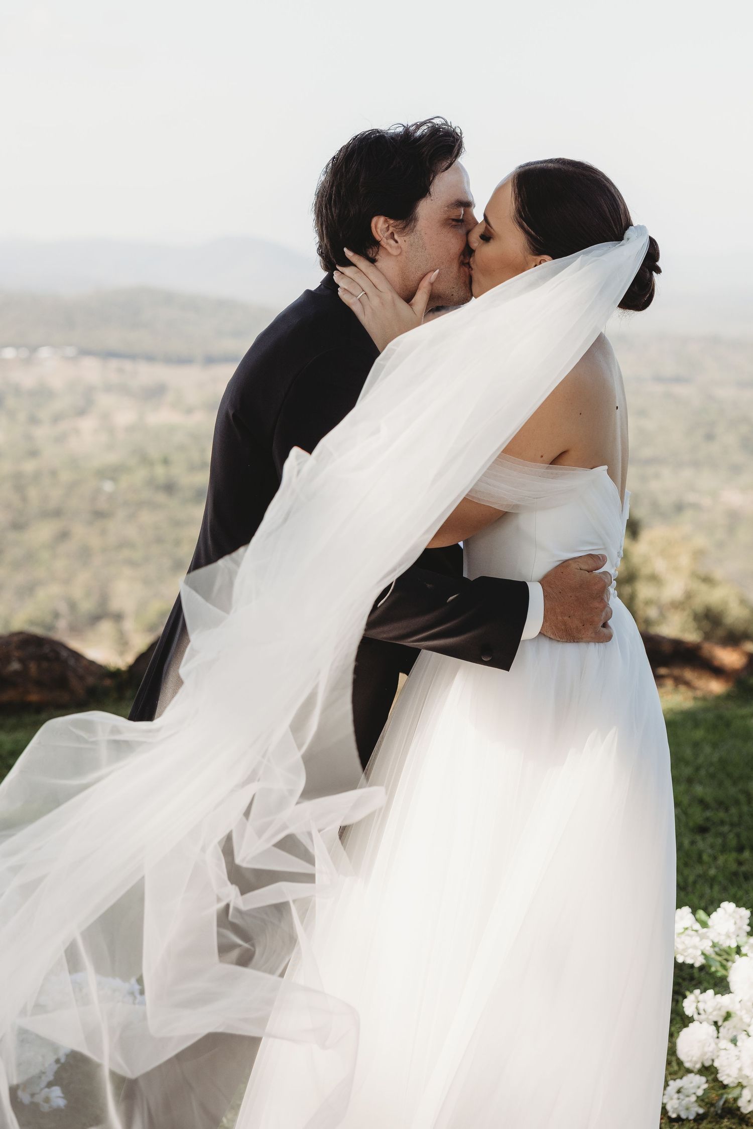 Series of romantic wedding kisses captured with a flowing veil against a scenic landscape.