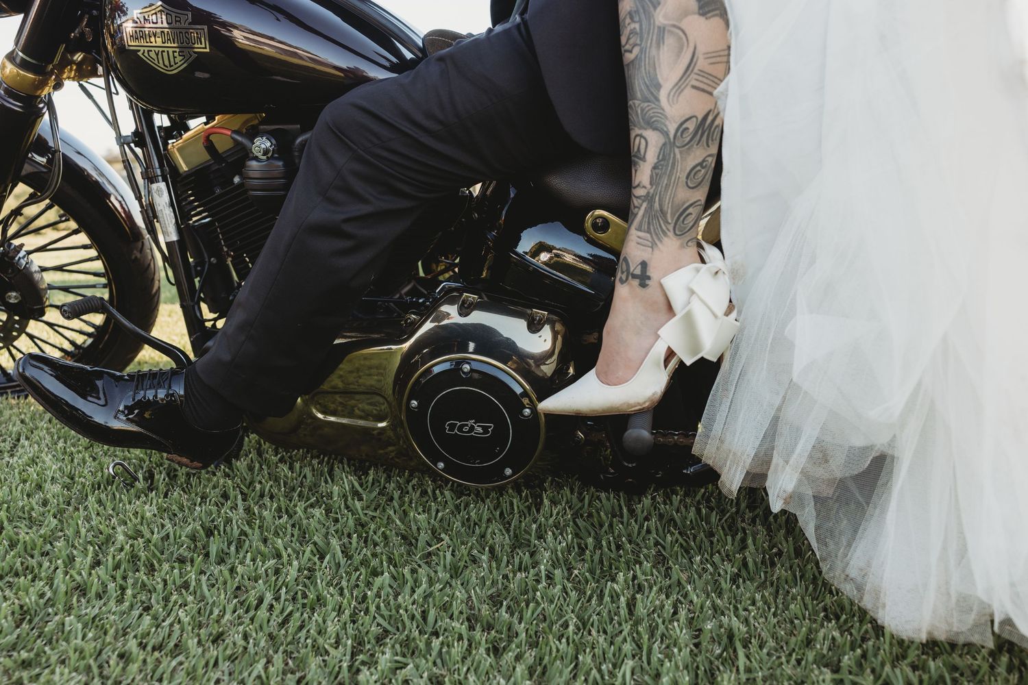 Close-up view of formal shoes and dress hem on green grass.