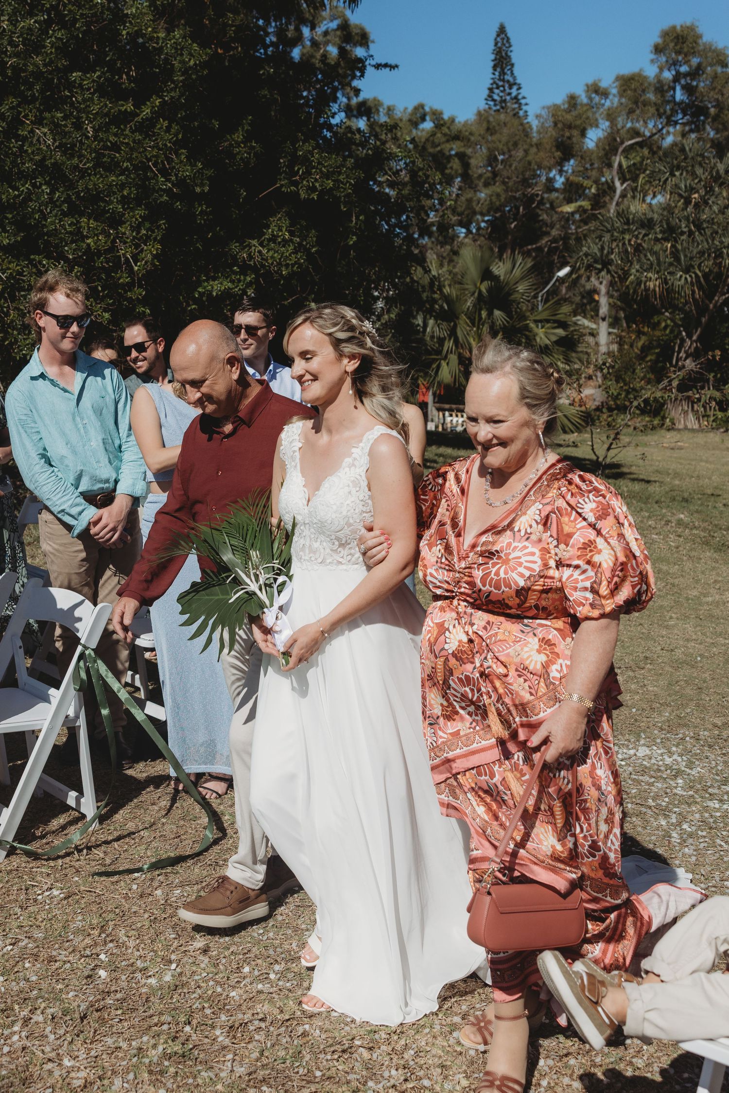 Wedding party members interacting outdoors on a sunny day.