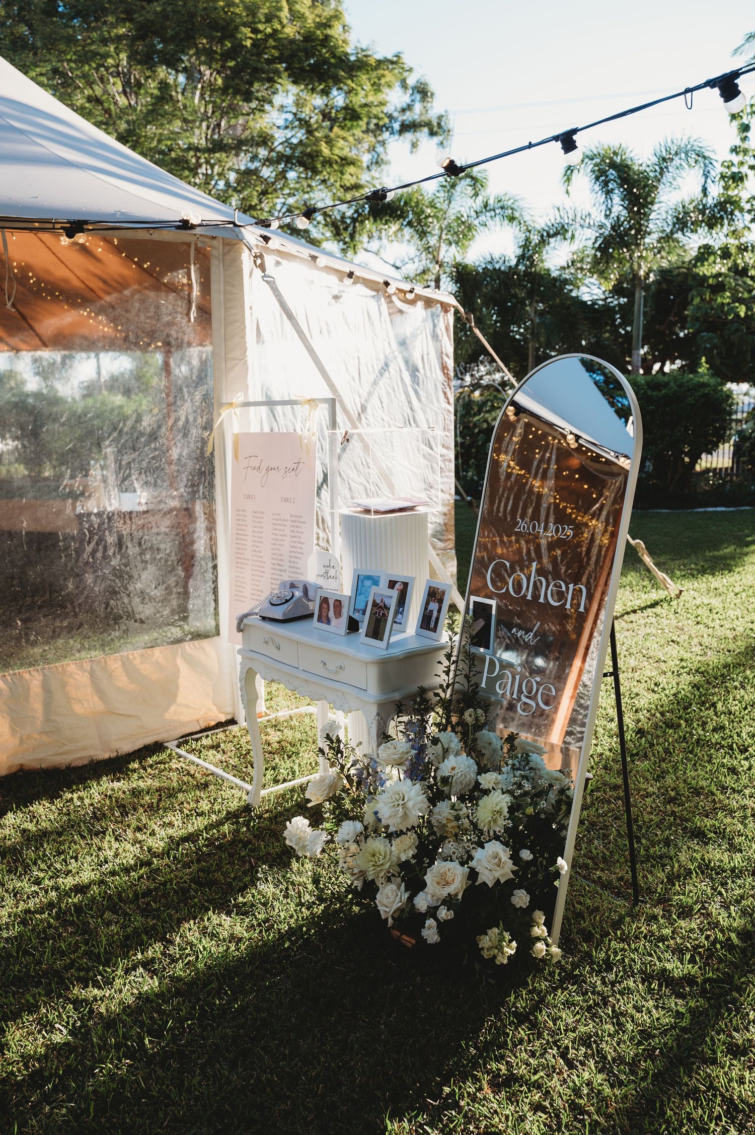 Clear tent setup outdoors with string lights and white floral decorations for an evening event rockhampton wedding