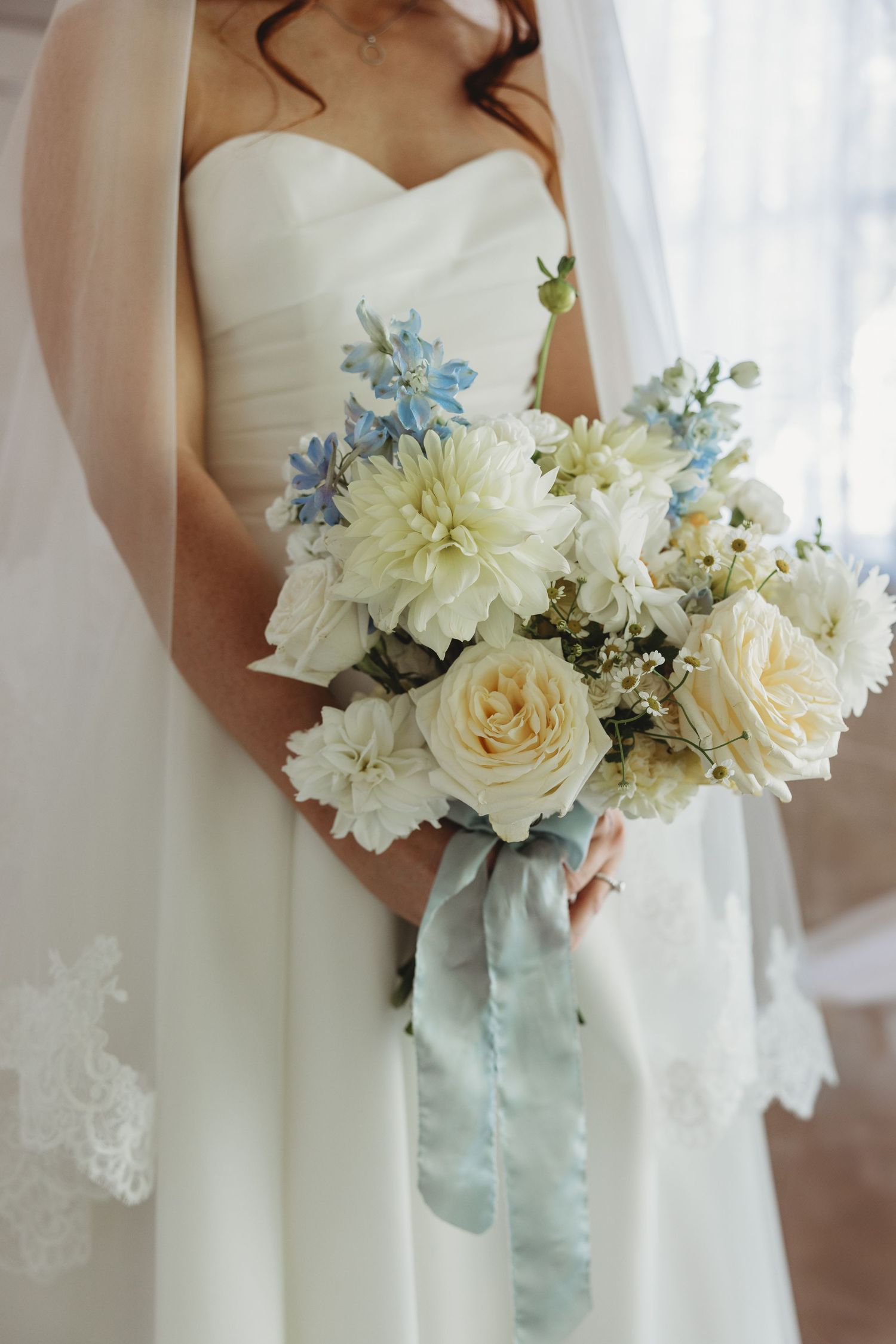 Close-up details of a bridal bouquet featuring white and blue flowers with soft ribbons. romantic bridal portrait at St Aubins Village Centr