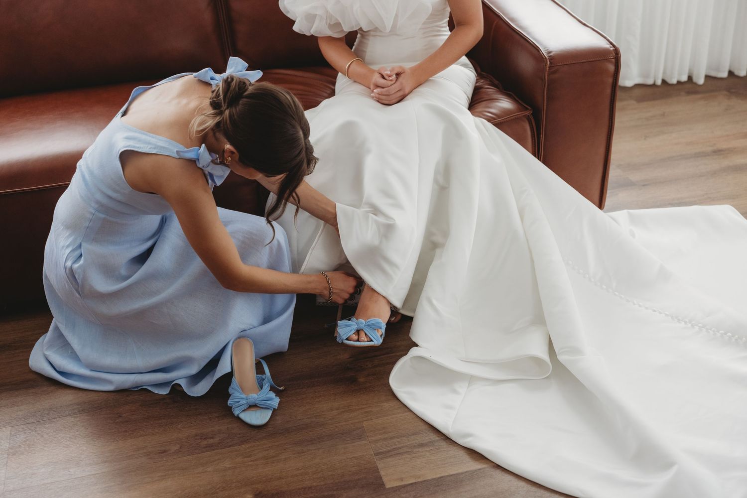 Wedding dress being fitted and adjusted on hardwood floor.