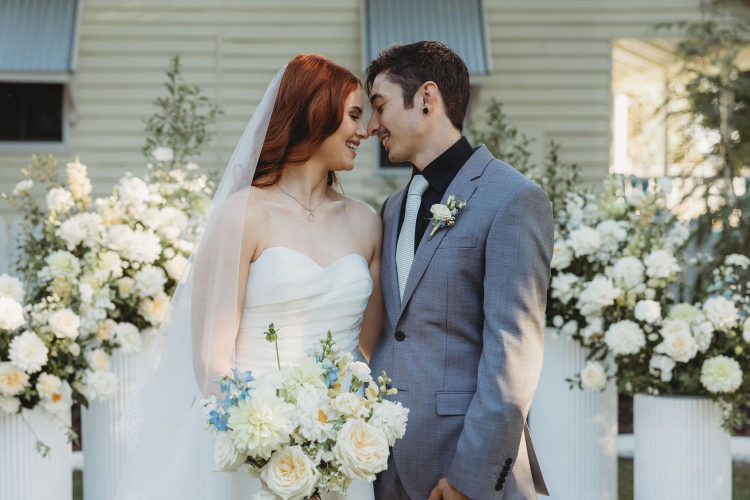 Elegant outdoor wedding ceremony with white floral arrangements and a grey suited groom central queenland wedding