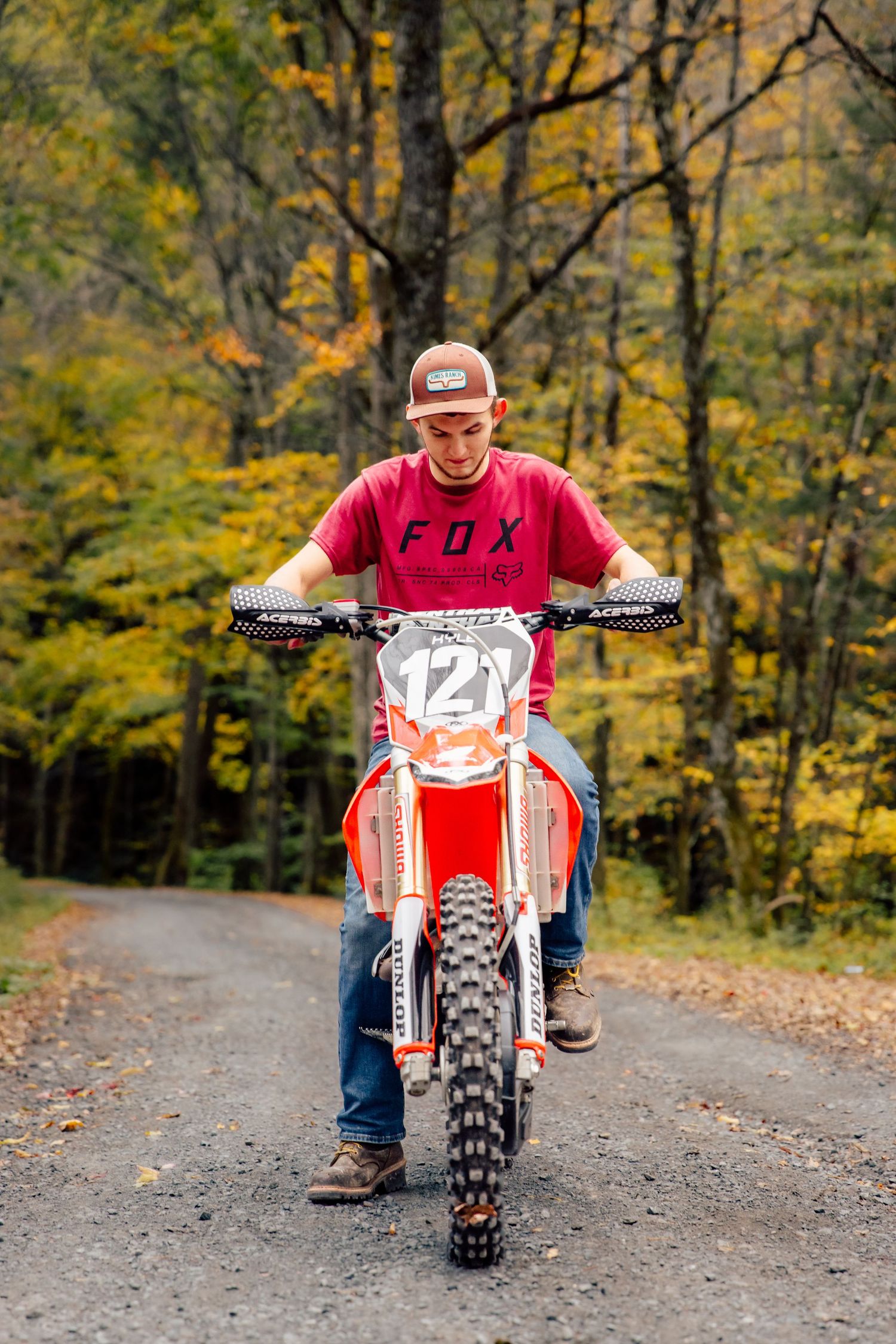 Boy posing with dirt bike on gravel road