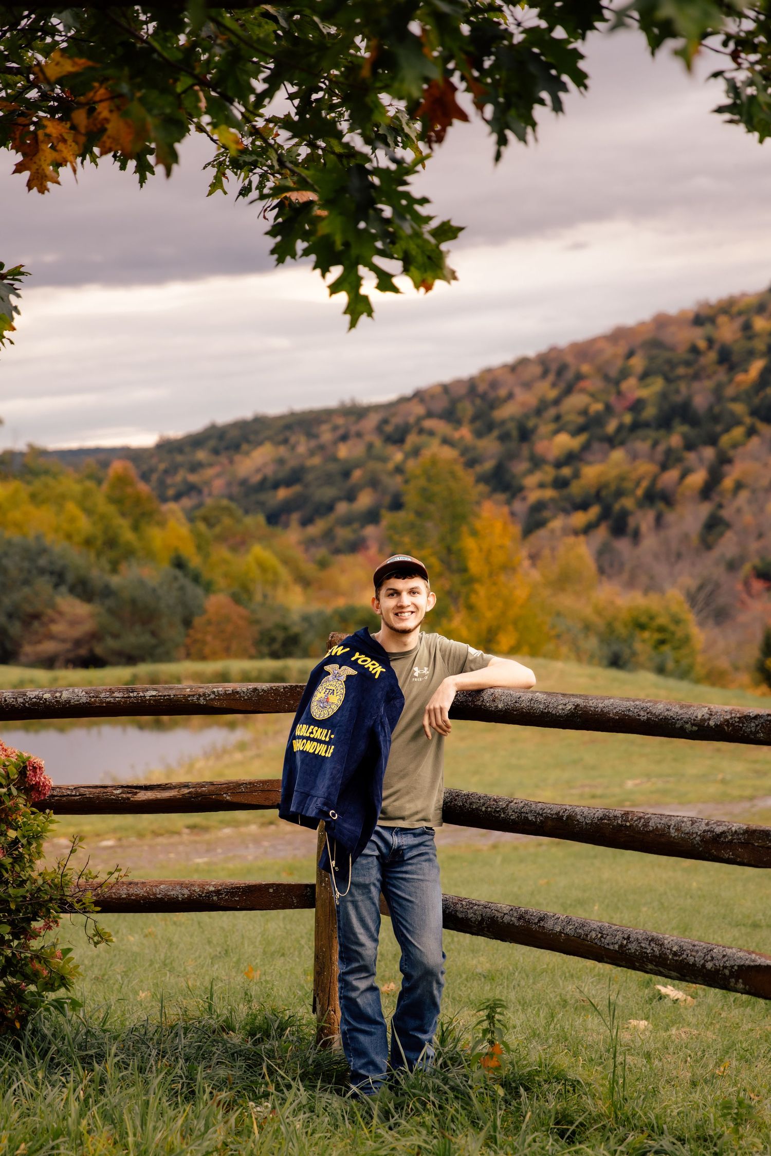 Boy leaning on fence with FFA jacket over his shoulder
