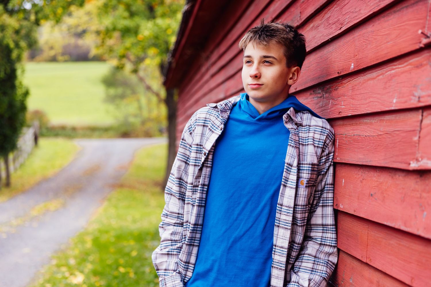 Boy leaning on red barn