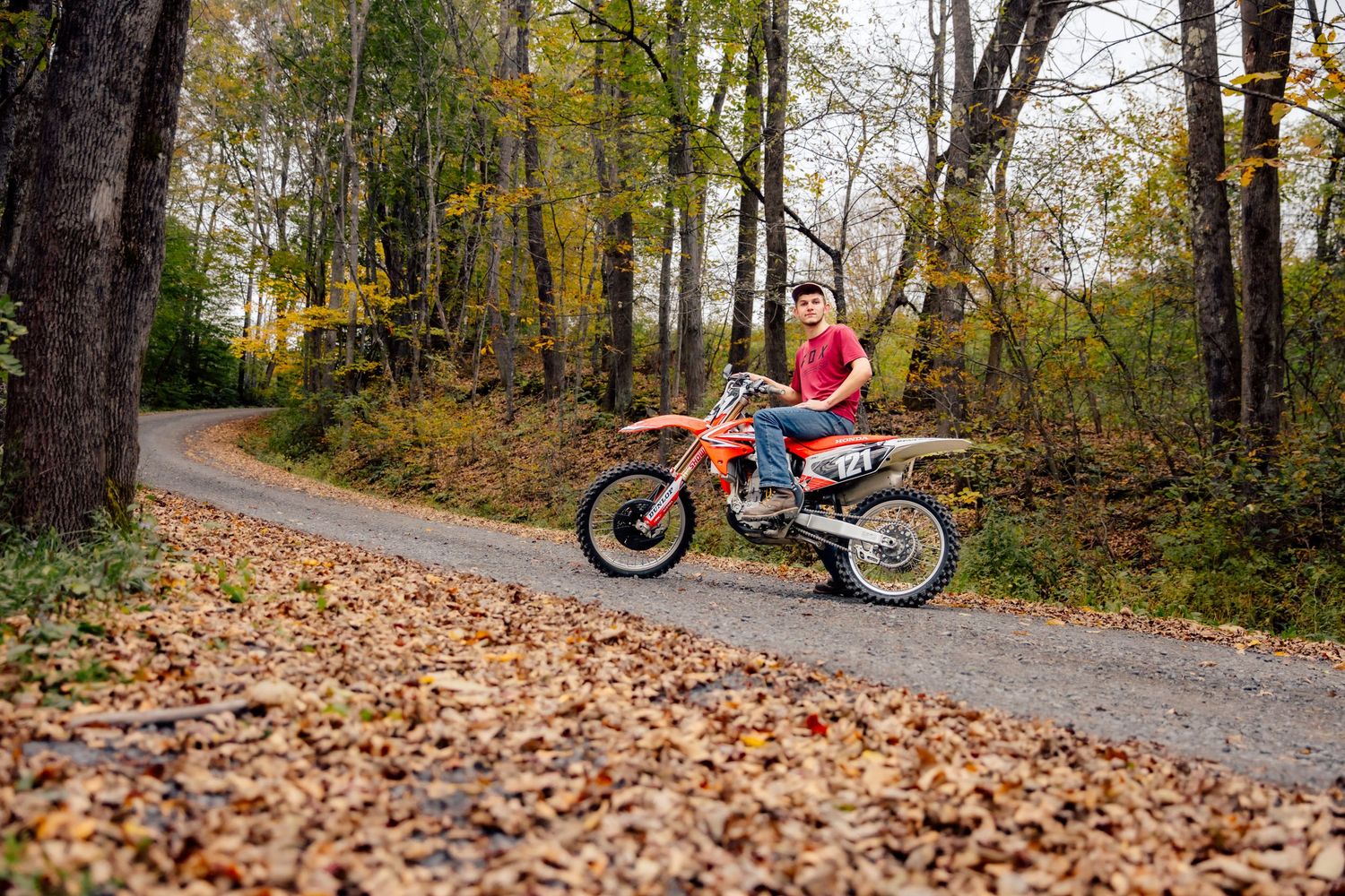 Boy posing with dirt bike on gravel road