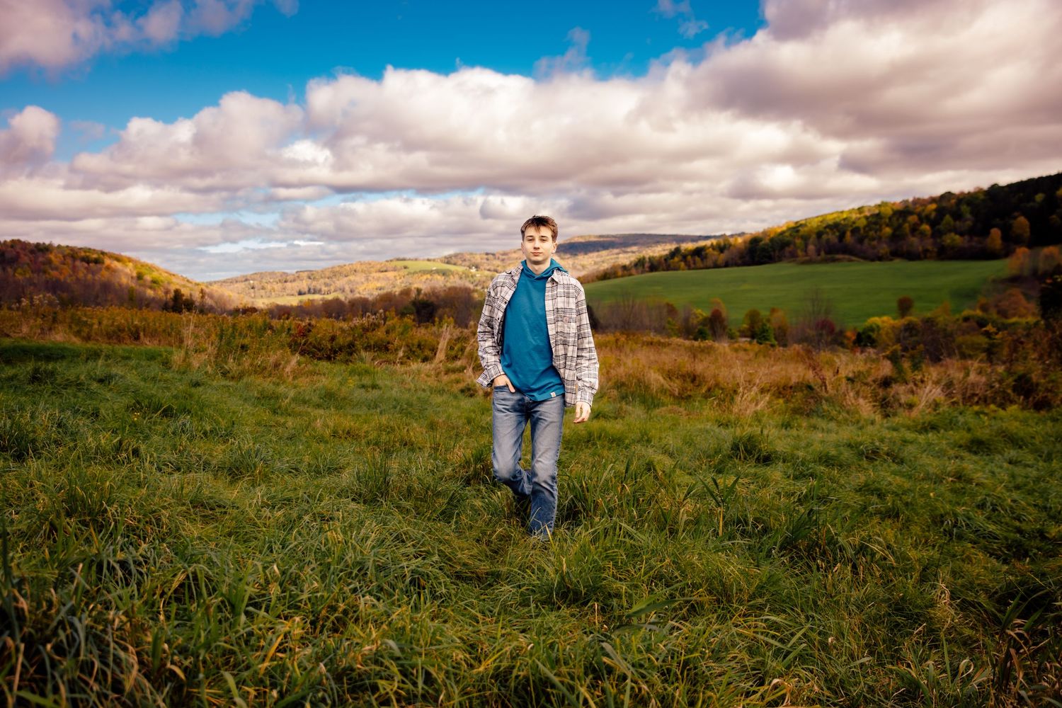 Boy walking through field with mountain view in background